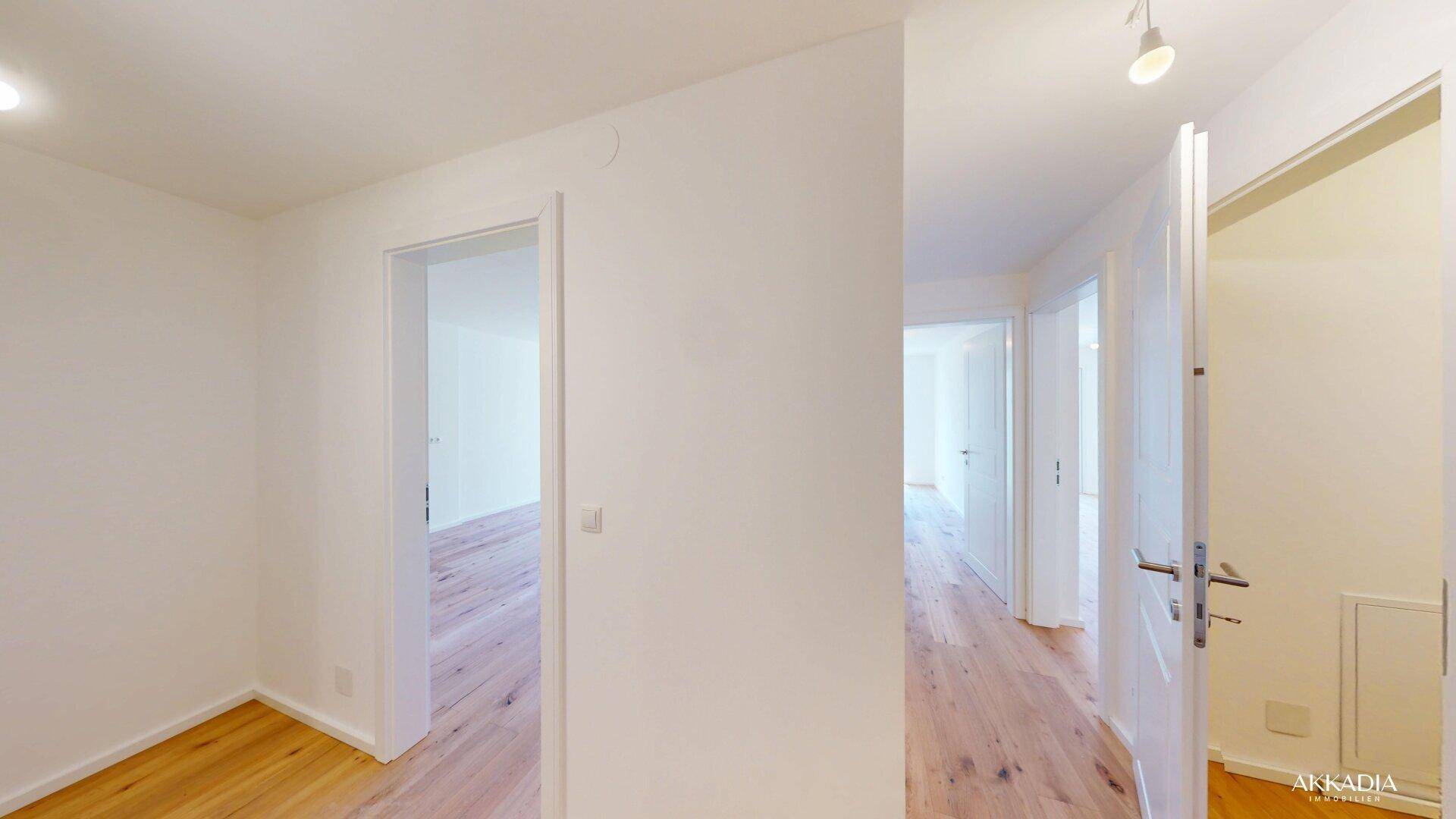 Heller Flur mit Holzboden und mehreren weißen Türen, die zu den angrenzenden Zimmern führen.