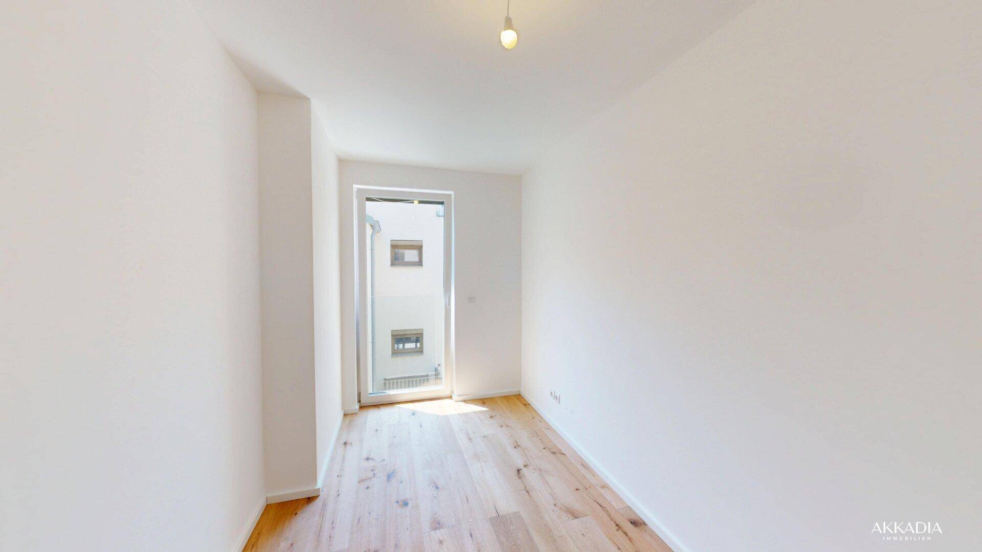 Heller Raum mit Holzboden und Zugang zu einem Außenbereich, der viel Tageslicht bietet.