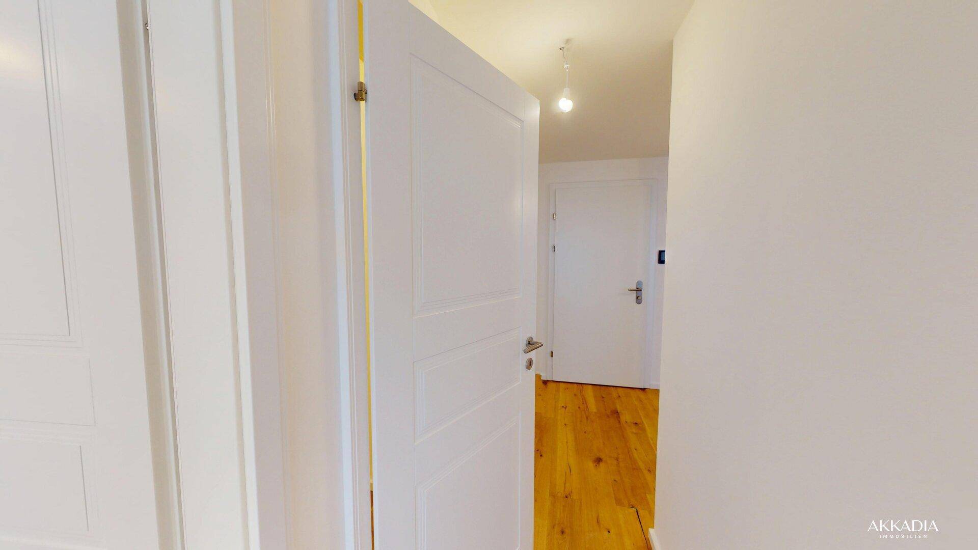 Heller Flur mit Holzboden und weißen Türen, der die verschiedenen Räume der Wohnung verbindet.