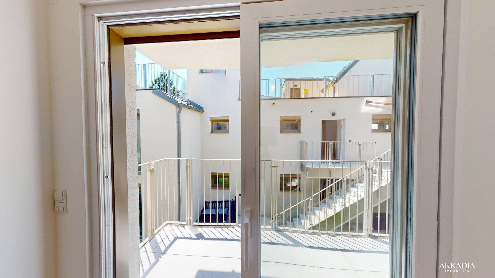 Große Glasschiebetür bietet Zugang zu einem Außenbereich mit Blick auf den modernen Innenhof.