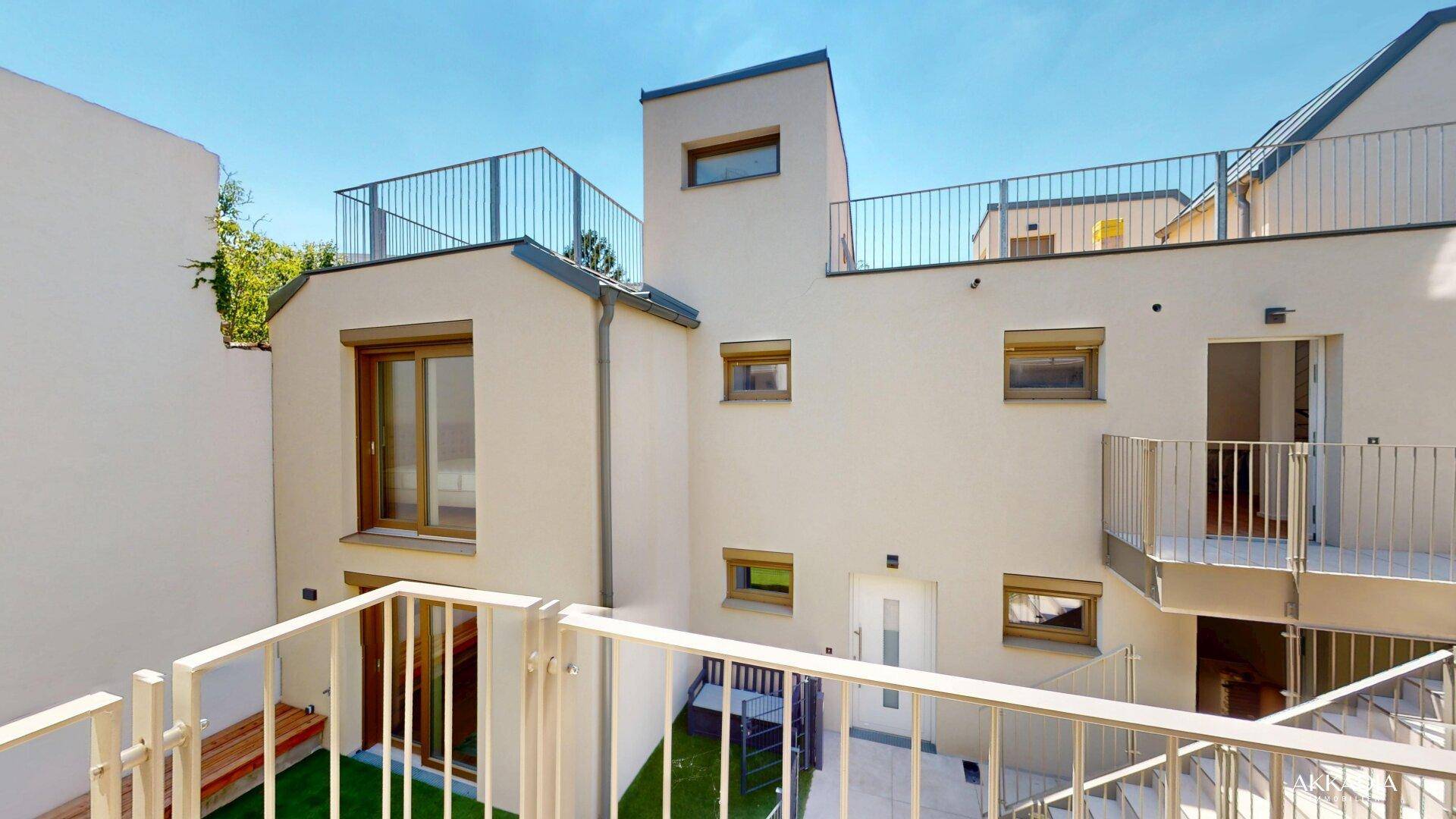 Sonniger Innenhof mit modernen Balkonen und Treppen, die die verschiedenen Ebenen des Gebäudes verbinden.
