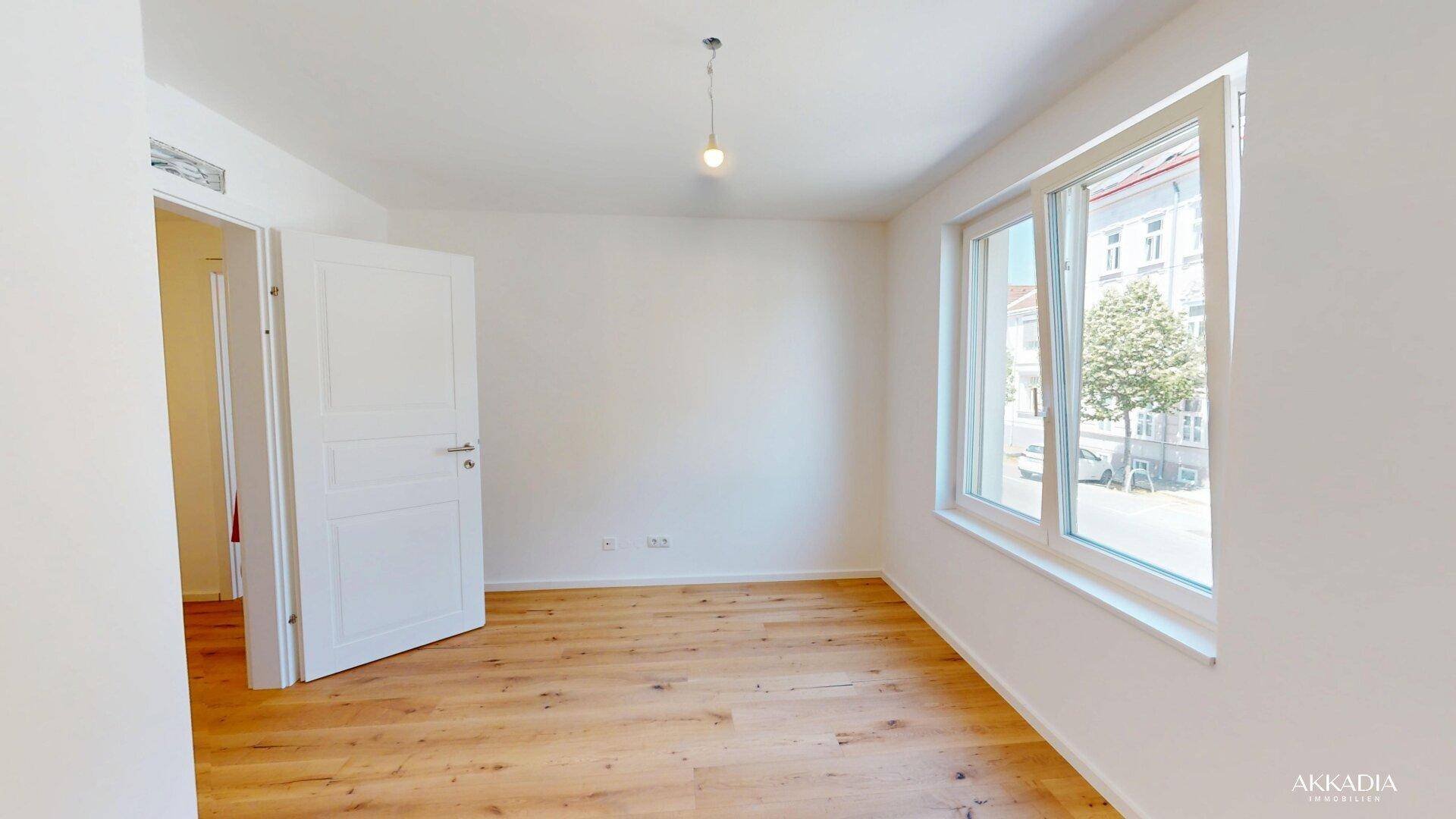 Lichtdurchflutetes Zimmer mit breitem Fenster und Holzboden, bereit zum Einrichten.