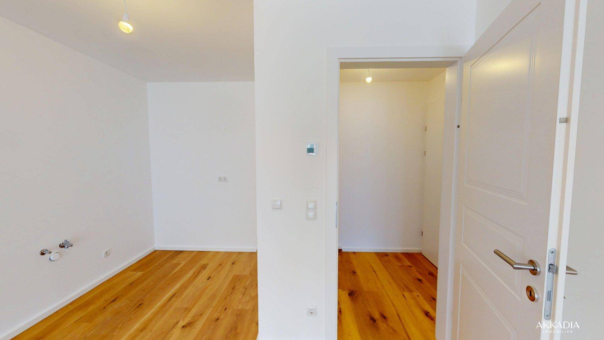Heller Raum mit Holzfußboden und weißen Wänden, vorbereitet für weitere Installationen.