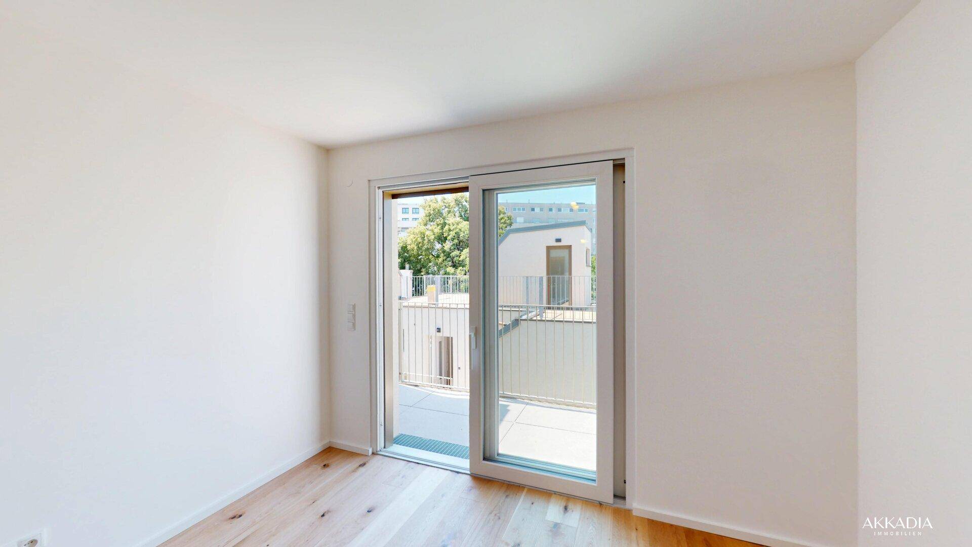 Helles Schlafzimmer mit Holzboden und großer Schiebetür, die zu einem Außenbereich führt.