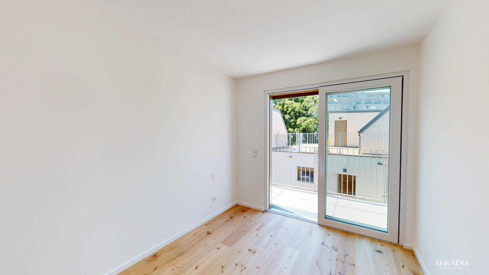 Helles Schlafzimmer mit Holzboden und großer Schiebetür, die zu einem Außenbereich führt.