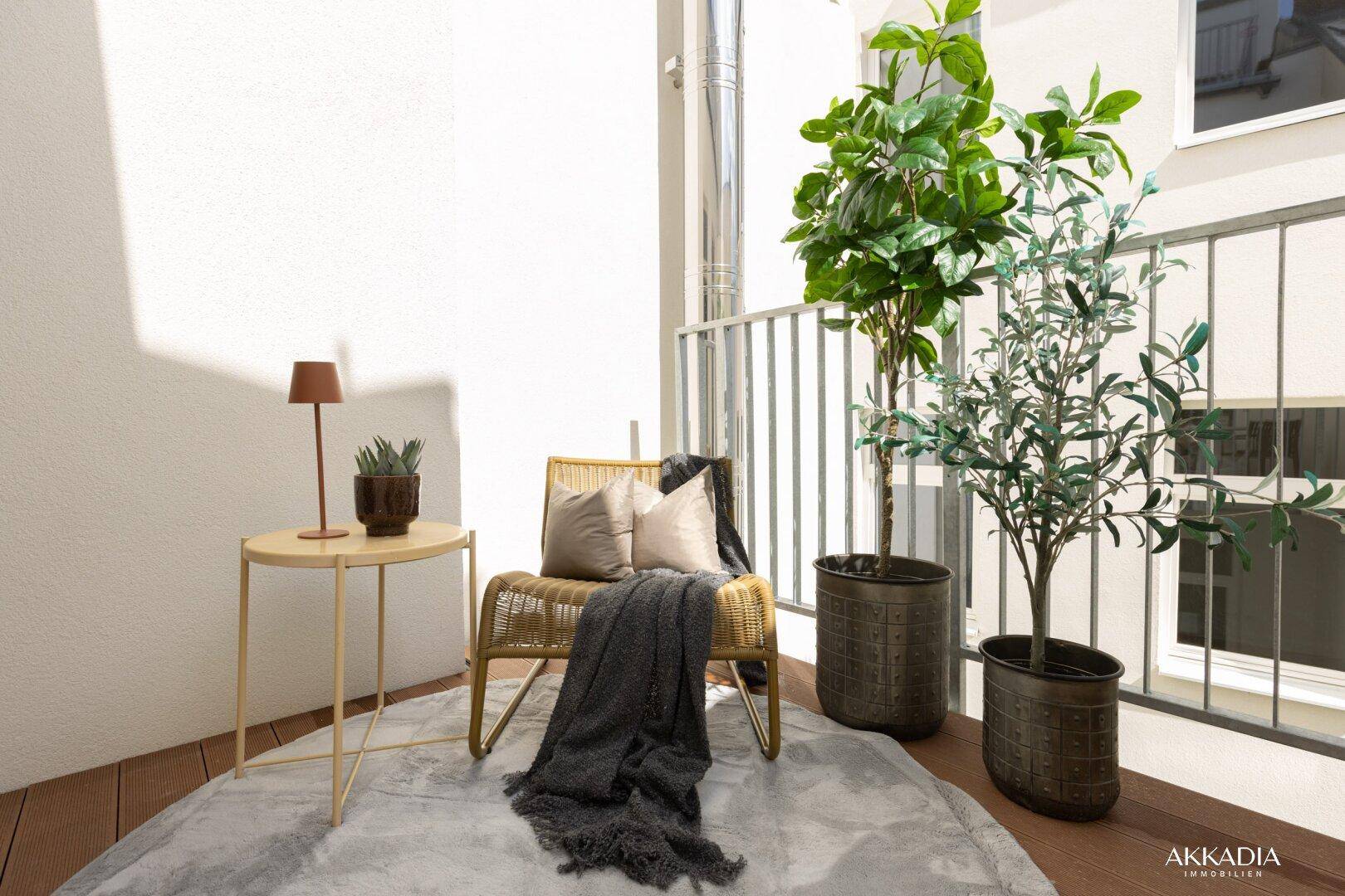 Gemütlicher Balkon mit Rattan-Sessel, Beistelltisch und Topfpflanzen für entspannte Stunden.