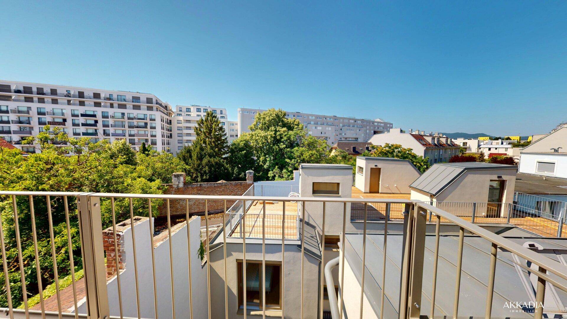 Weitläufiger Ausblick über die Dächer der Stadt mit umliegenden Wohngebäuden und viel Grün.