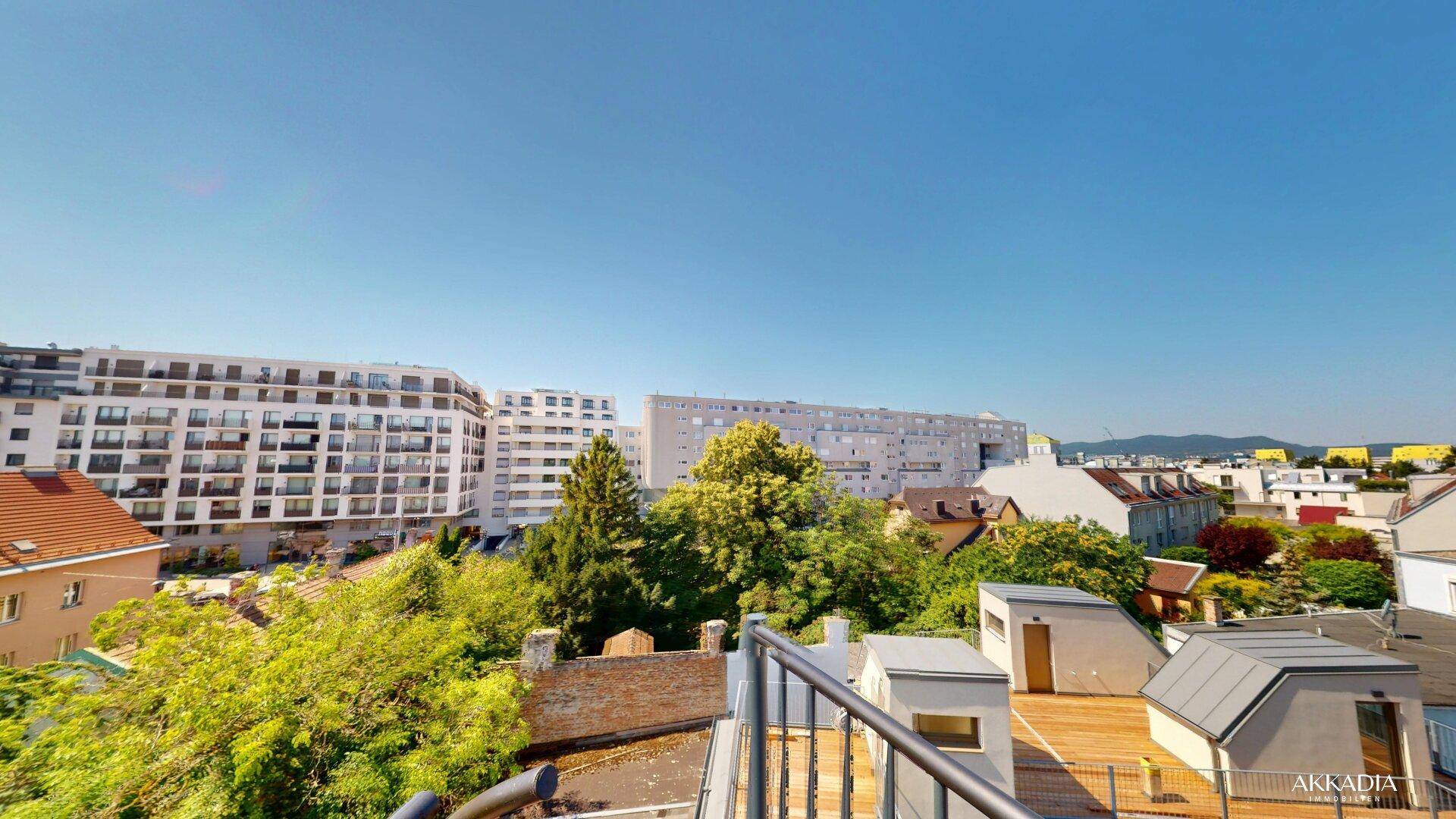 Weitläufiger Blick von der Dachterrasse über die städtische Umgebung mit vielen Bäumen und Gebäuden.