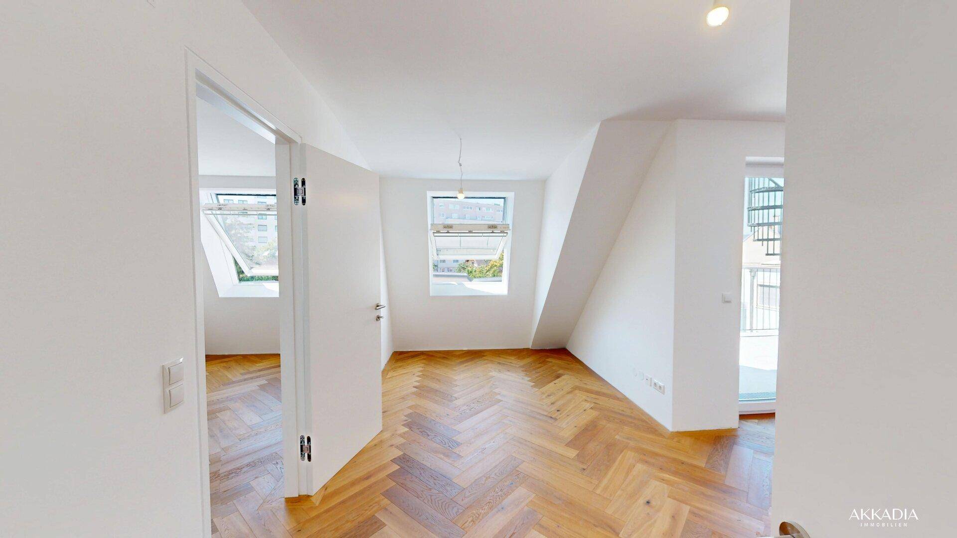 Heller Raum mit Fischgrätparkett, Dachschrägen und Fenstern, ideal als Schlafzimmer.