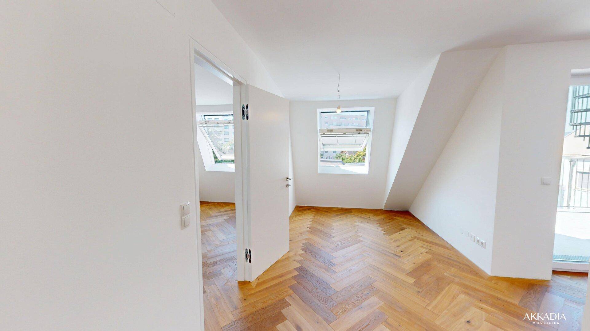 Heller Raum mit Fischgrätparkett, Dachschrägen und Fenstern, ideal als Schlafzimmer.