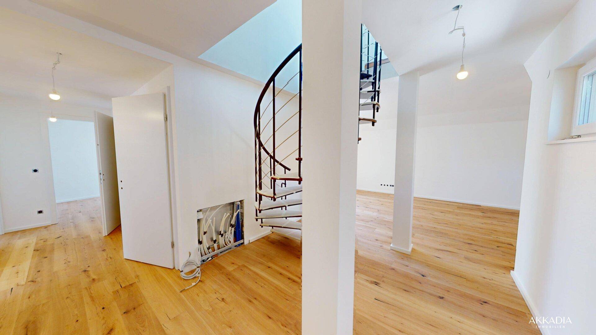 Heller Flurbereich mit eleganter Wendeltreppe und sichtbaren Installationen für zukünftige Einbauten.