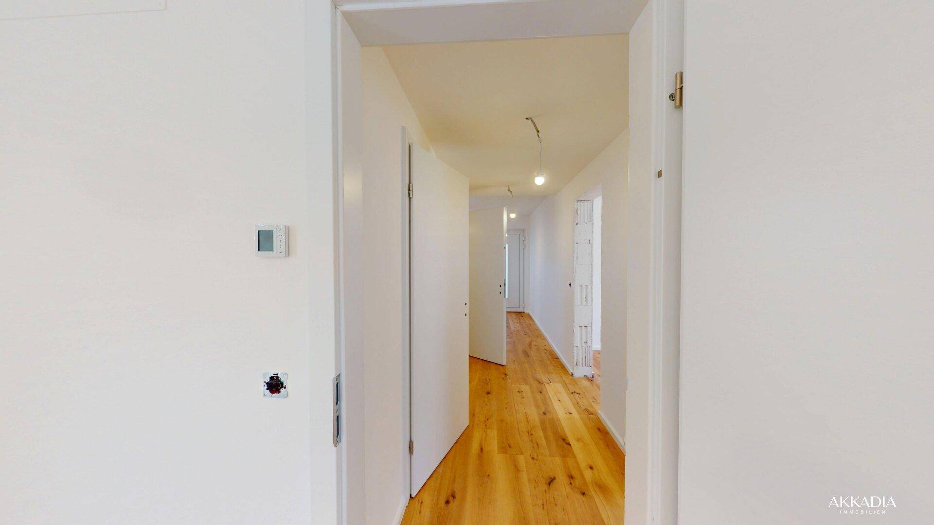 Langer, heller Flur mit Holzparkettboden, der zu weiteren Zimmern der Wohnung führt.
