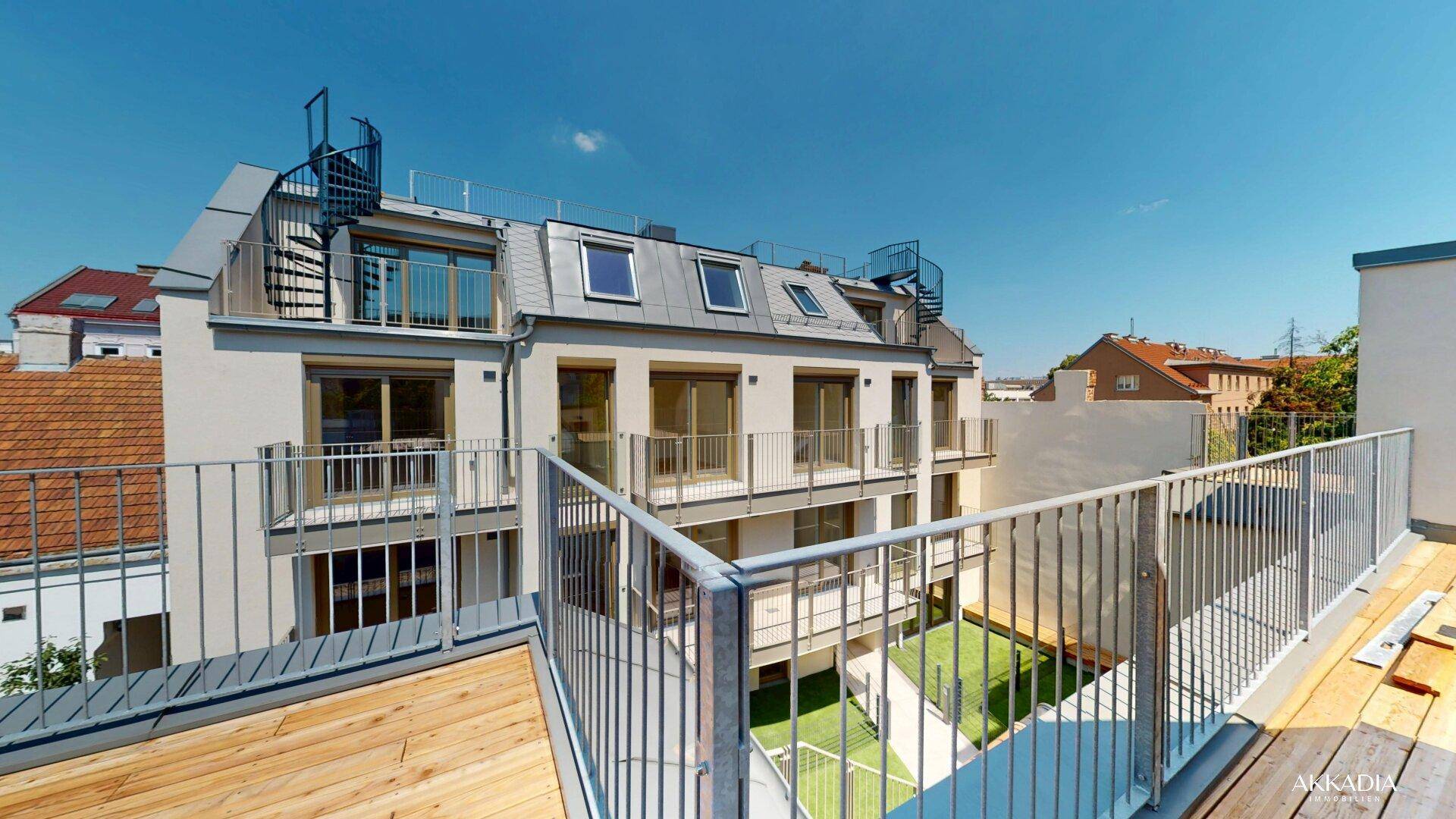 Dachterrasse mit Holzboden und Blick auf das moderne Gebäude und den Innenhof.