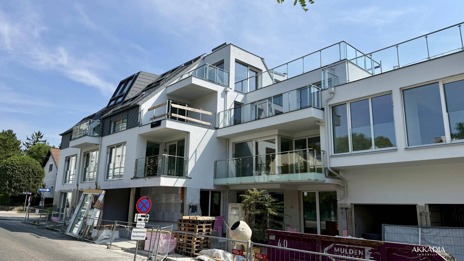 Fassade des Neubaus mit zahlreichen Balkonen, großen Fensterfronten und Glasgeländern während der Bauphase.