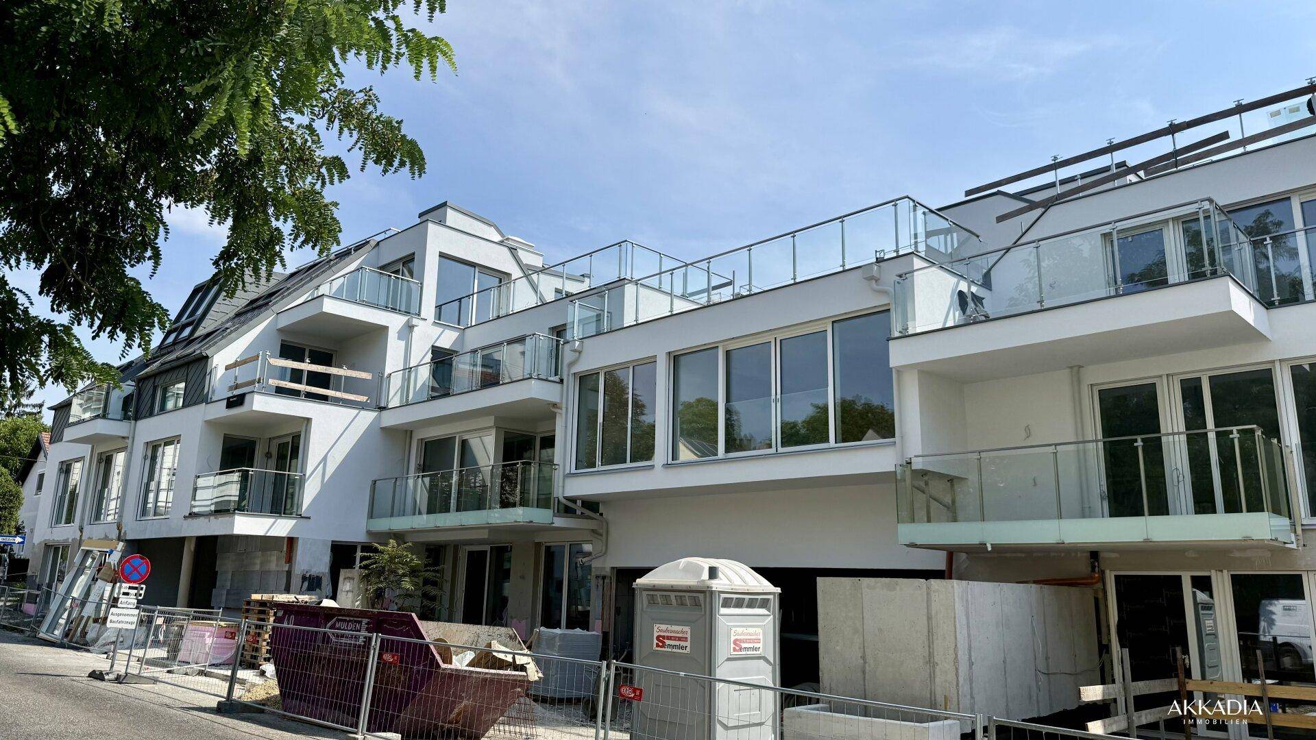 Fassade des im Bau befindlichen Wohngebäudes mit Balkonen, großen Fenstern und Baustelleninfrastruktur.