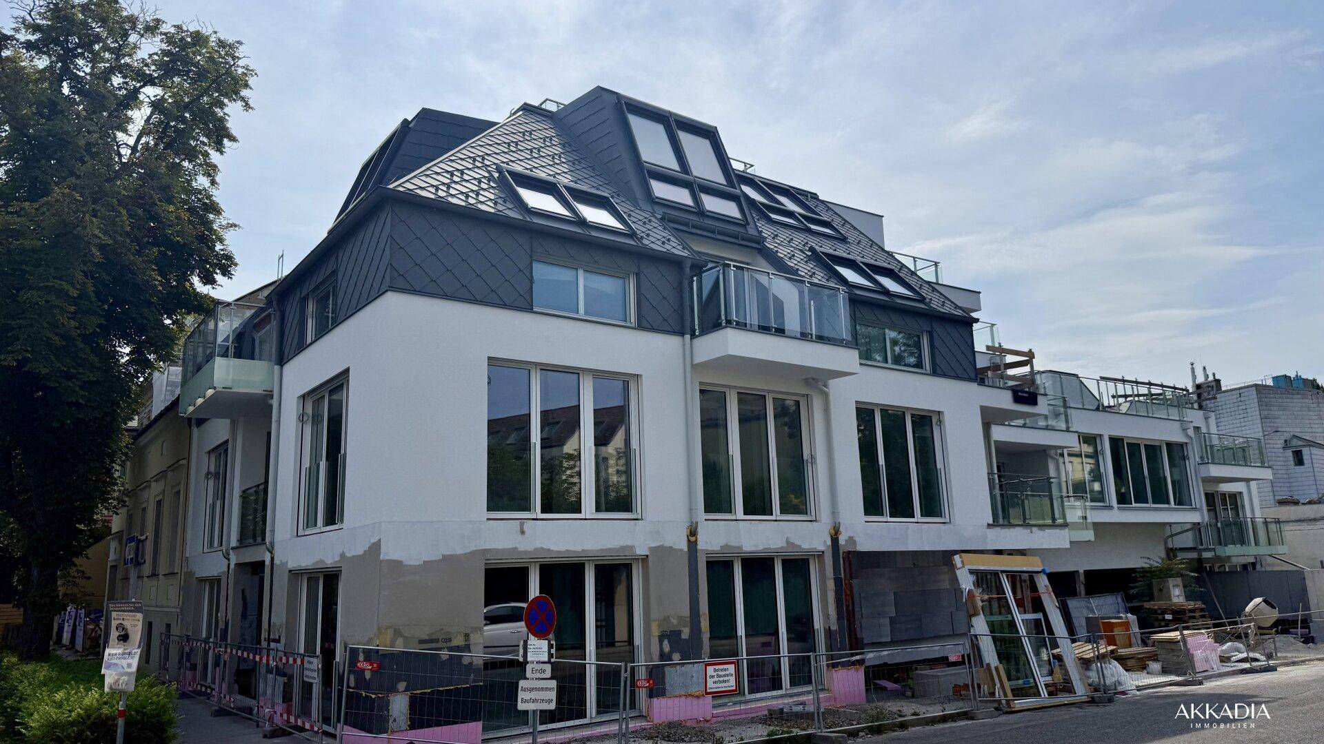 Eckansicht des modernen Neubaus mit weißer Fassade, großen Fenstern und Balkonen.