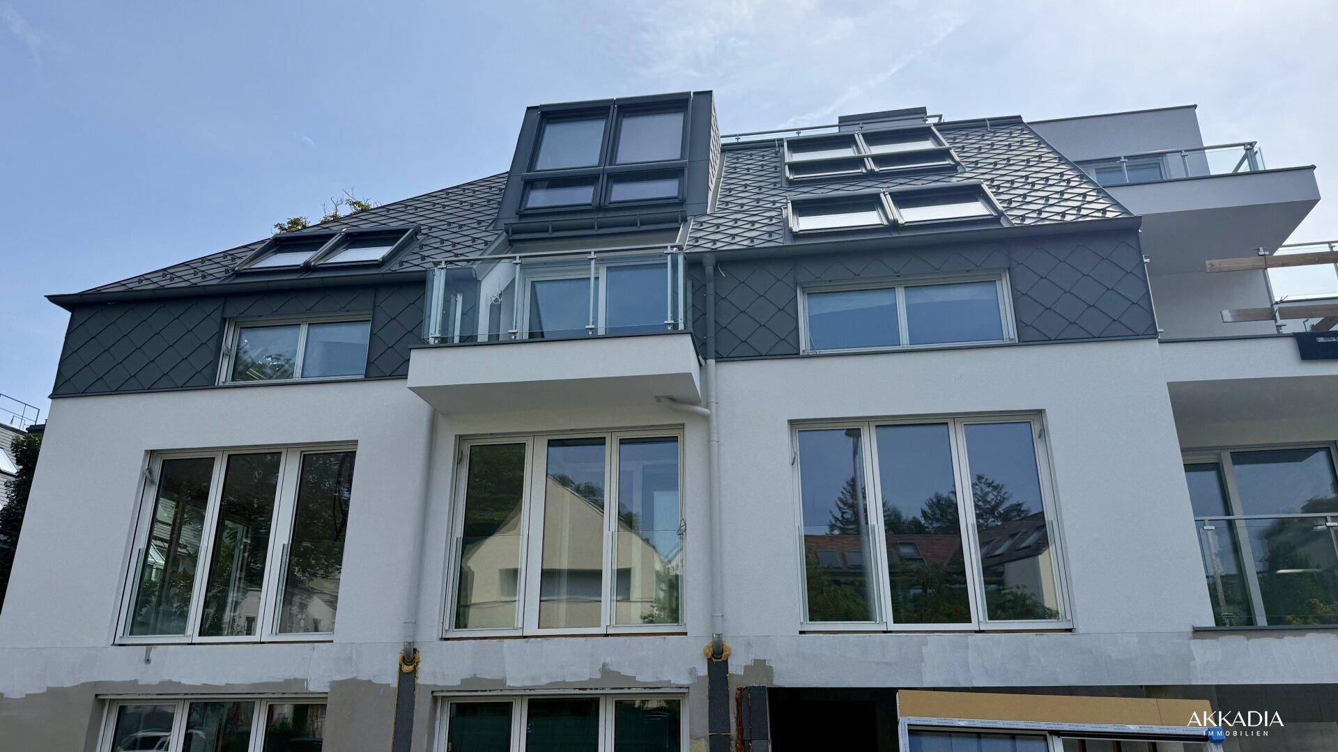 Detailansicht der modernen Fassade mit zahlreichen Dachfenstern und Balkonen.