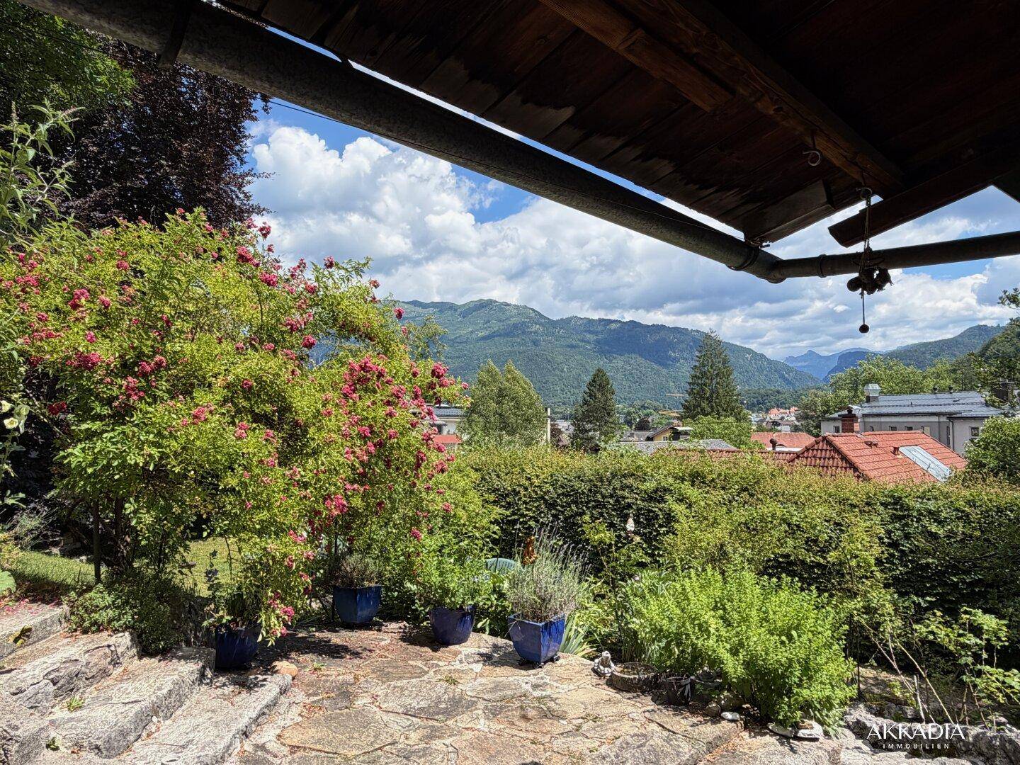 Steinplatten-Terrasse mit Bergblick, umgeben von üppiger Vegetation und Pflanzen.