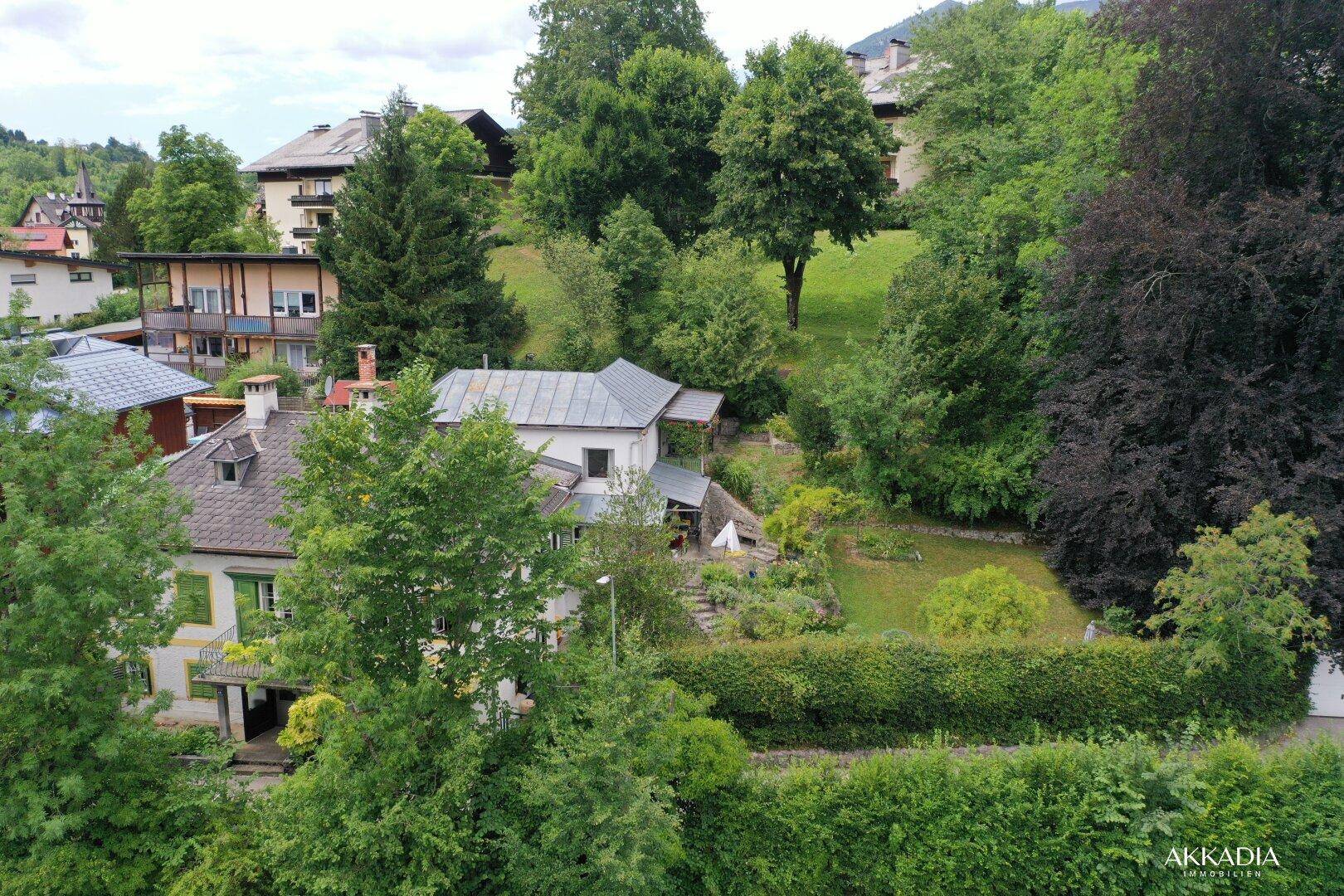 Übersicht des Anwesens mit großem Garten, umgeben von Bäumen und Hügeln.