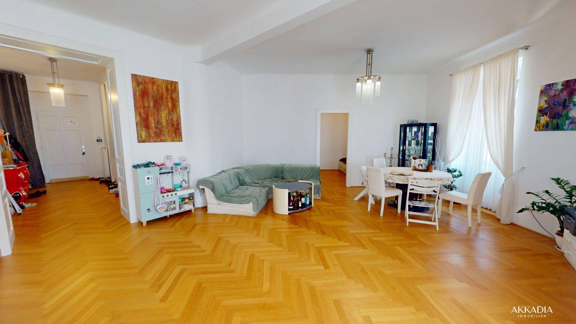 Geräumiger Wohn- und Essbereich mit Fischgrätparkett, Sofa und Esstisch, ideal für Familien.