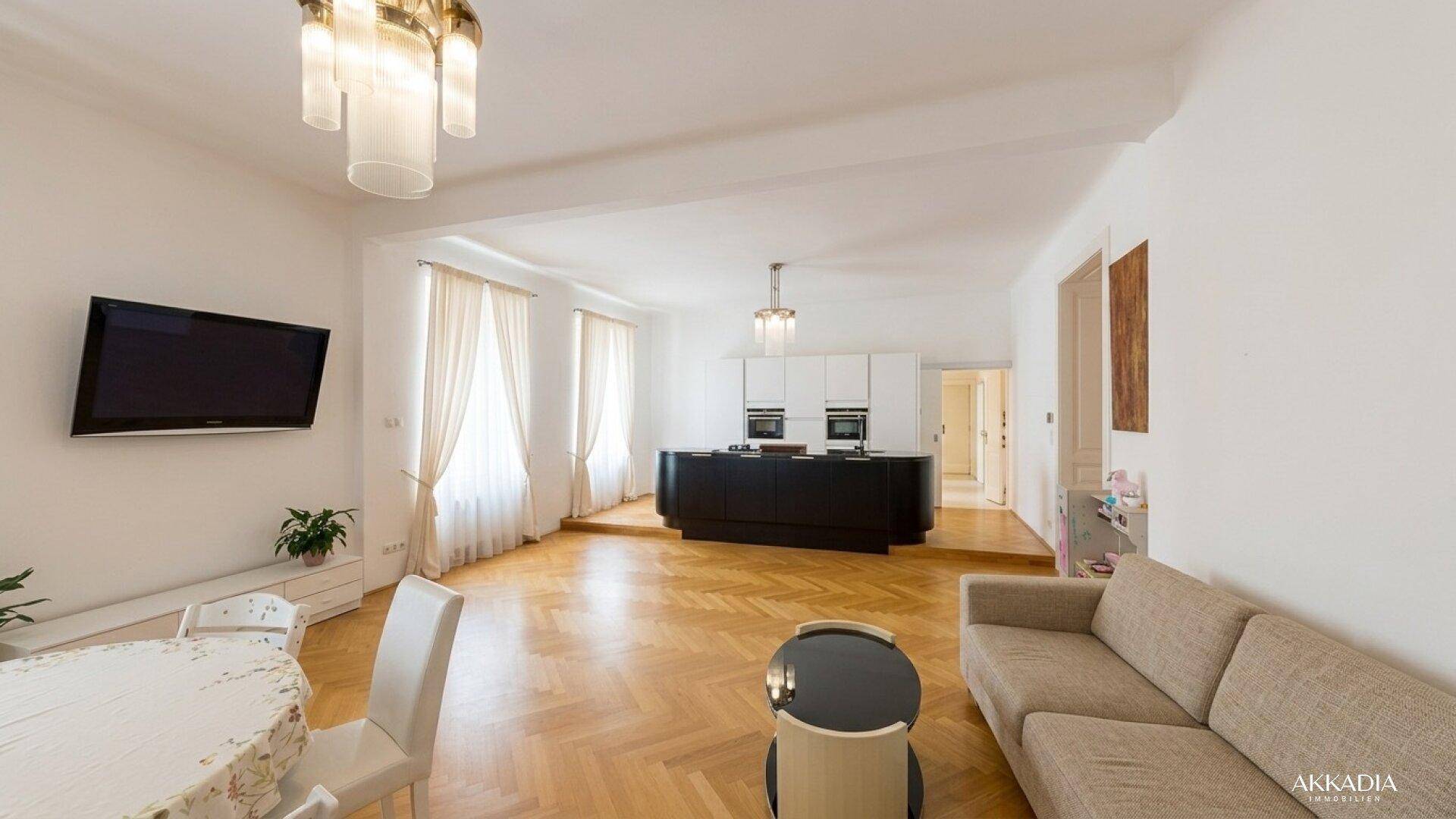 Heller Wohn- und Essbereich mit Sofa, Esstisch und offener Küche im Hintergrund.