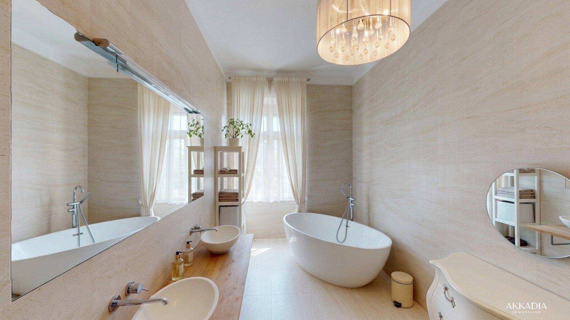 Elegantes Badezimmer mit freistehender Badewanne, Doppelwaschbecken und großen beigefarbenen Fliesen.
