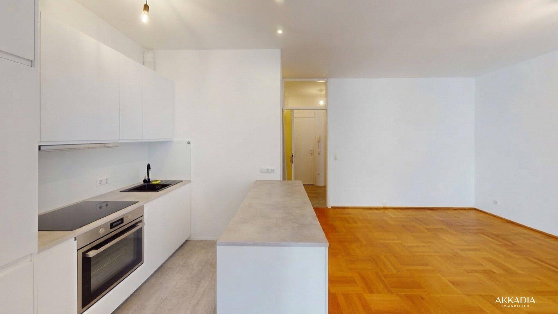Moderne Einbauküche mit weißen Schränken, Induktionskochfeld und offener Gestaltung zum Wohnbereich.