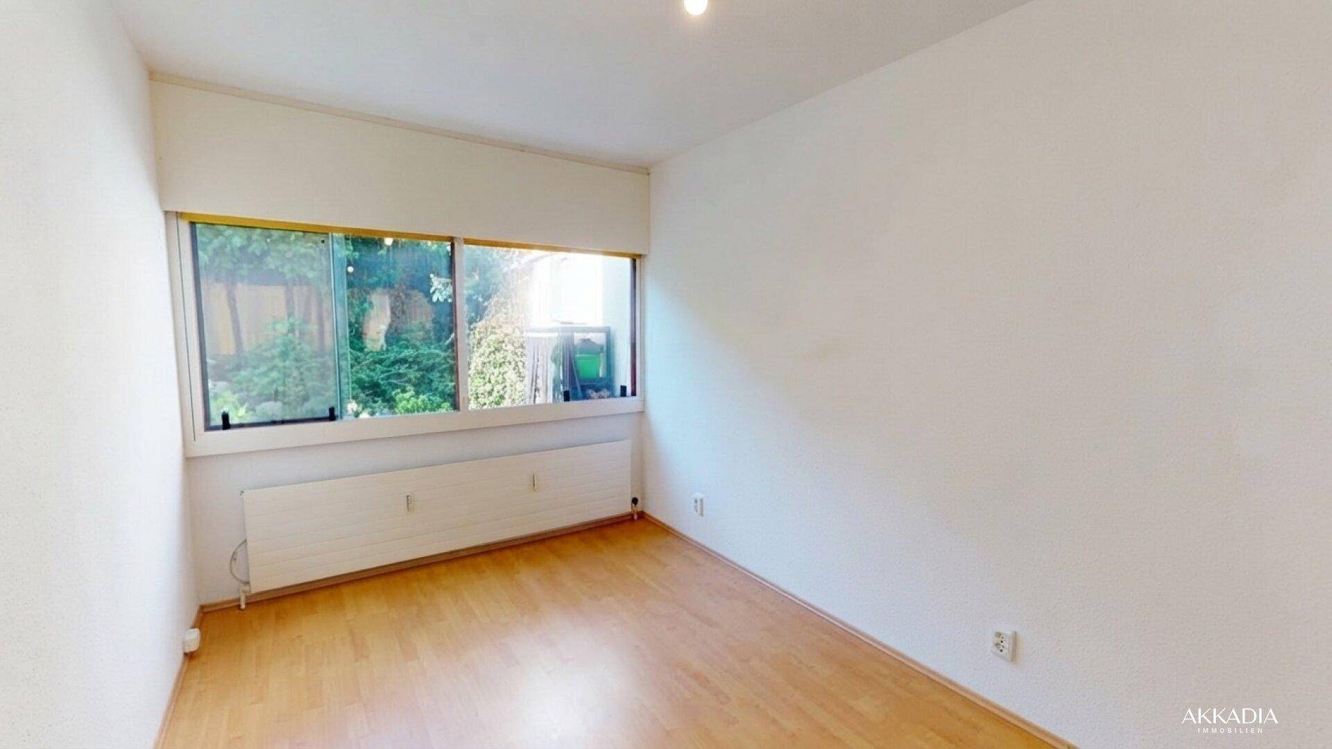 Heller, leerer Raum mit großen Fenstern und Parkettboden, ideal als Wohn- oder Schlafzimmer.
