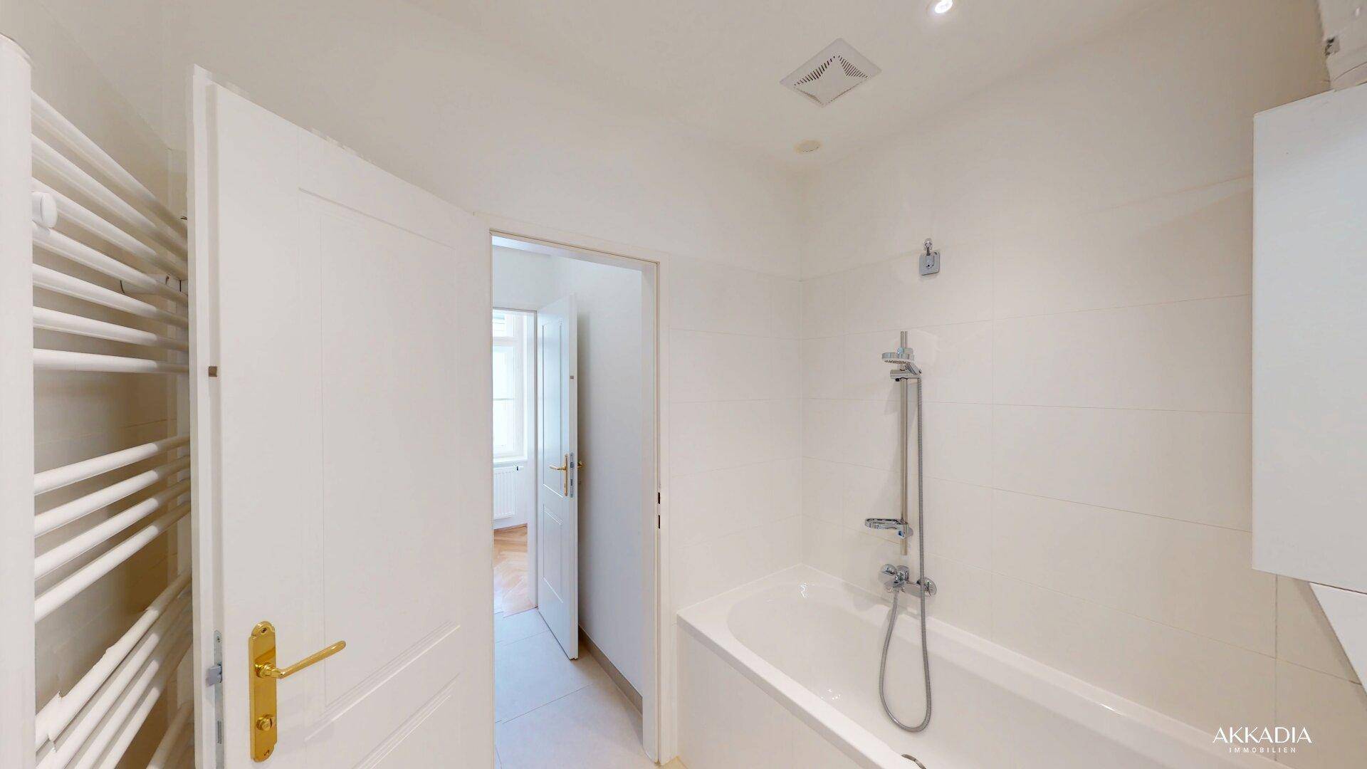 Helles Badezimmer mit Badewanne, Duscharmatur und beheiztem Handtuchhalter.