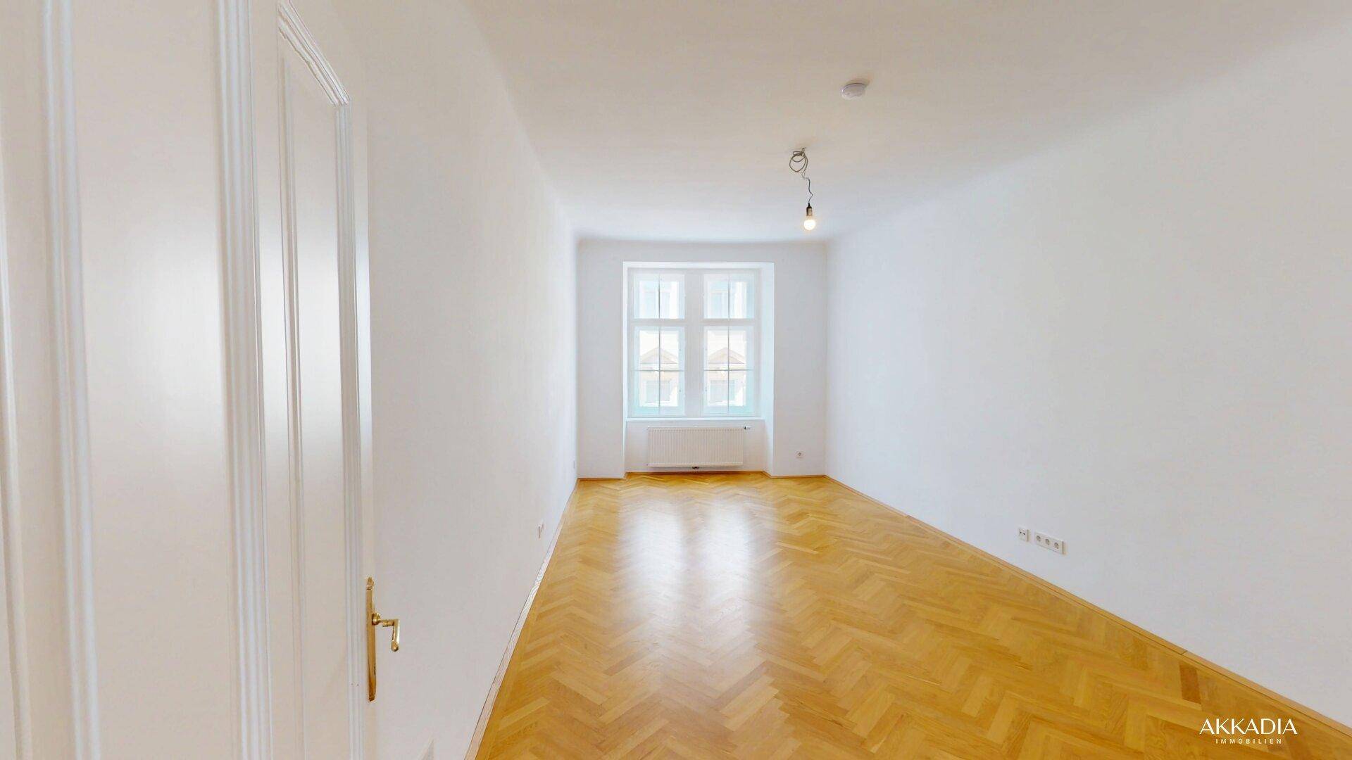 Unmöbliertes Schlafzimmer mit Fischgrätparkett und großem Fenster für viel Tageslicht.