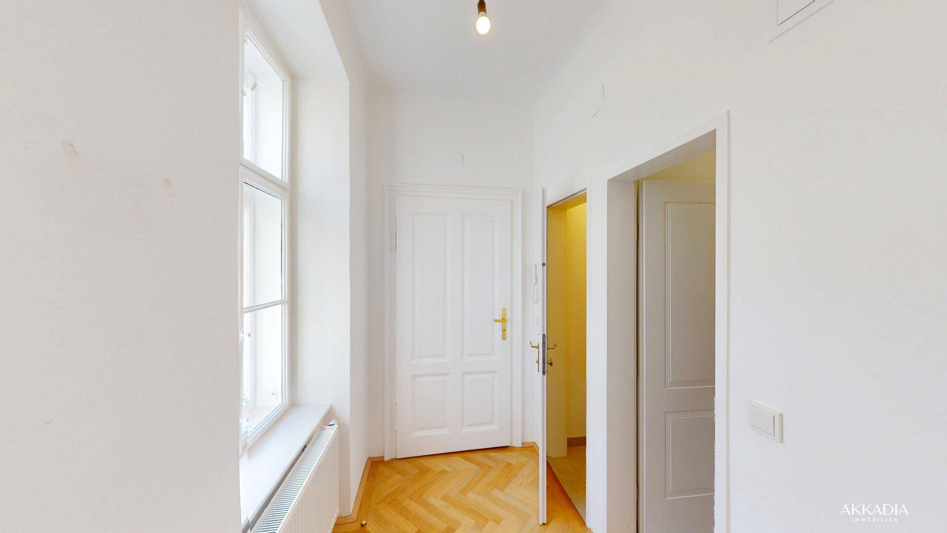 Heller Flur mit Fischgrätparkett und klassischen weißen Türen.
