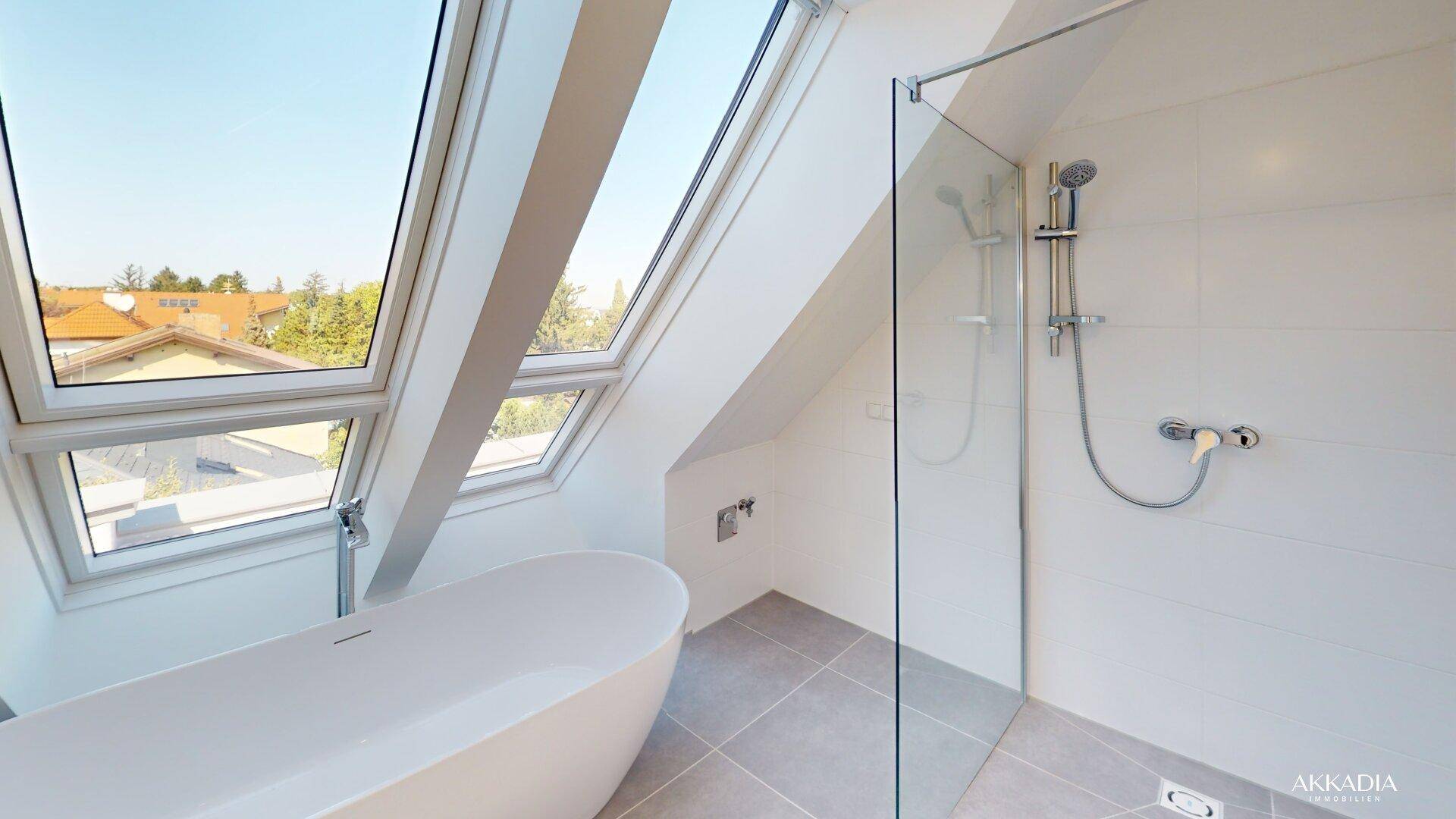 Modernes Badezimmer mit freistehender Badewanne, Glasdusche und großen Dachfenstern.