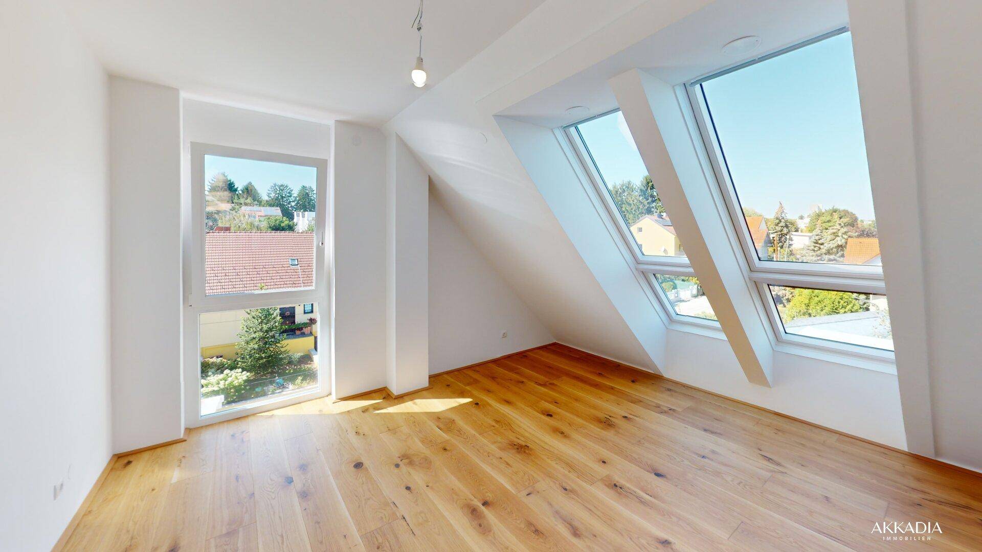 Helles Schlafzimmer mit Holzboden und großen Fenstern, inklusive Dachfenstern, für viel Licht.