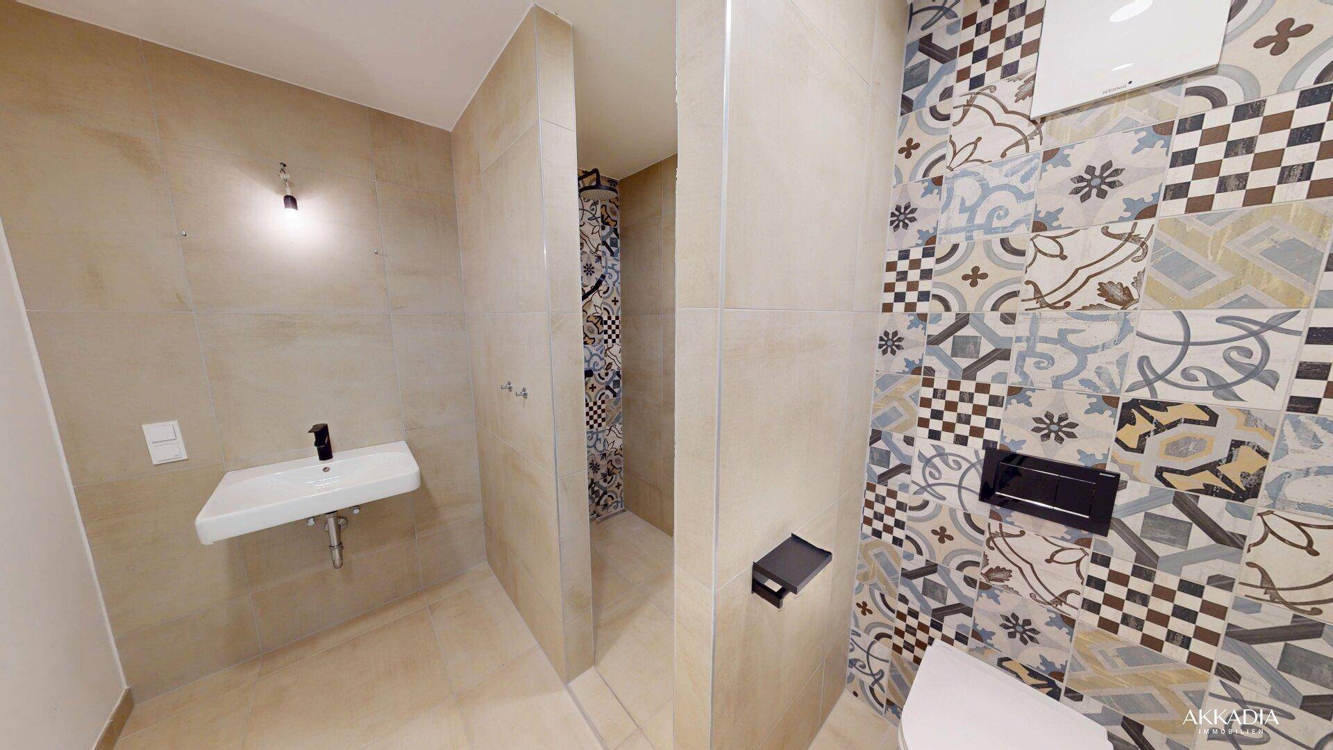 Modernes Badezimmer mit gemusterten Fliesen, wandhängendem WC und Einzelwaschbecken.