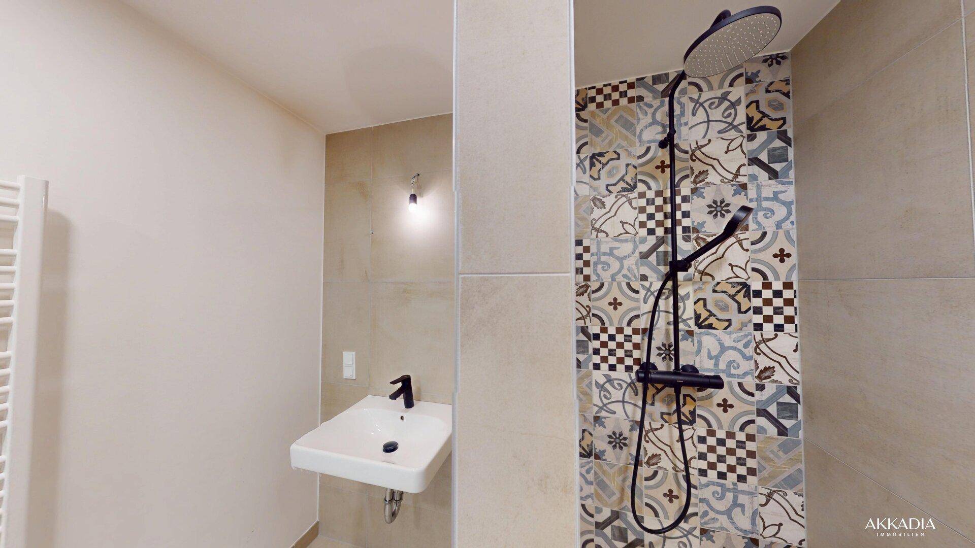 Modernes Badezimmer mit gemusterten Fliesen in der Dusche, einem einzelnen Waschbecken und Handtuchheizkörper.