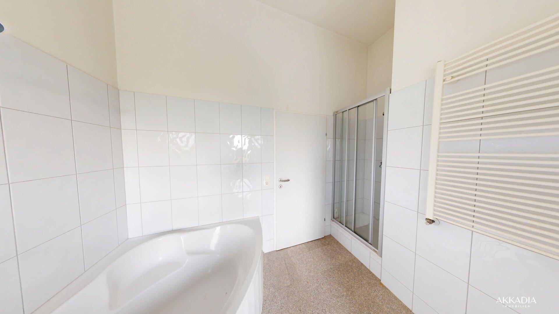 Badezimmer mit weißen Fliesen, Badewanne, Duschkabine und beheiztem Handtuchhalter.