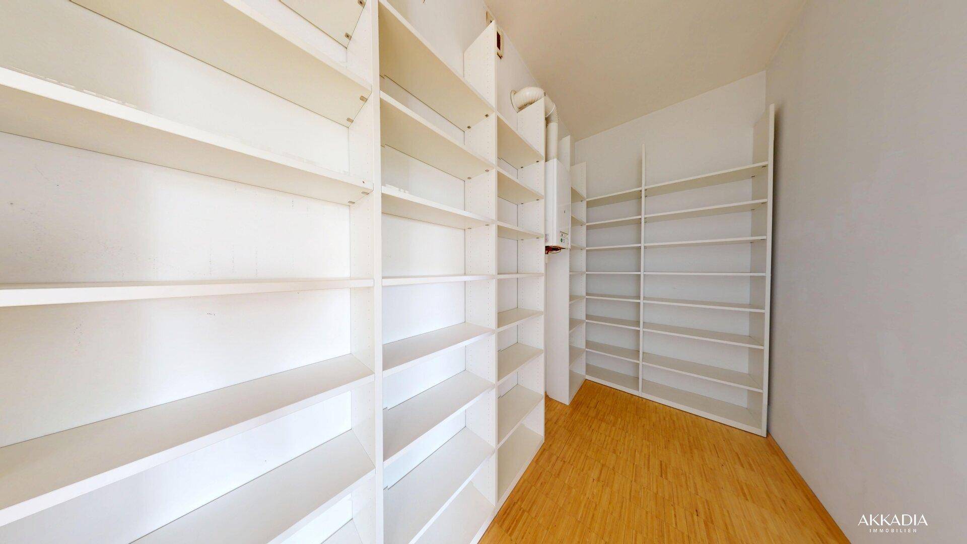 Raum mit vielen weißen Einbauregalen und Holzfußboden, ideal als Büro oder Bibliothek.