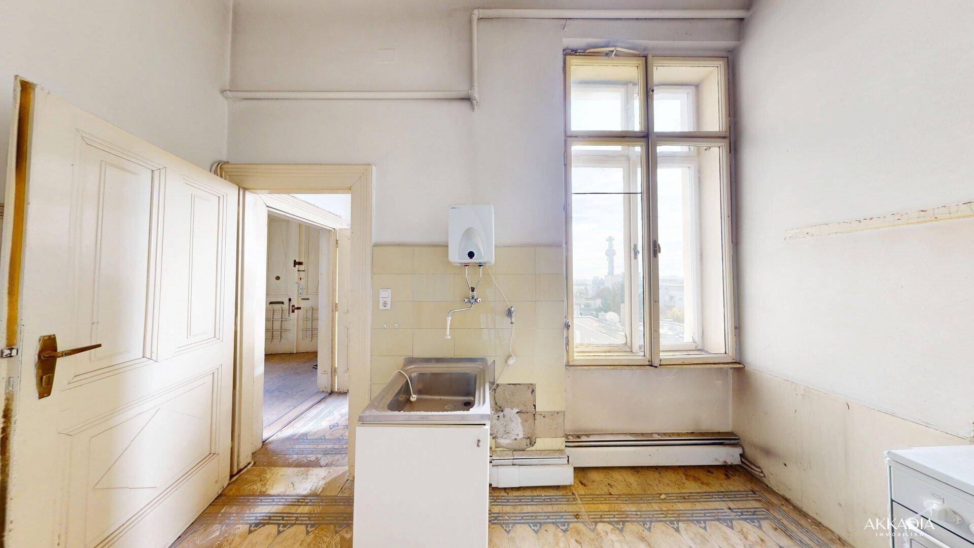 Einfache Küche mit Spülbecken, Boiler und Fliesenboden, die dringend renoviert werden muss.