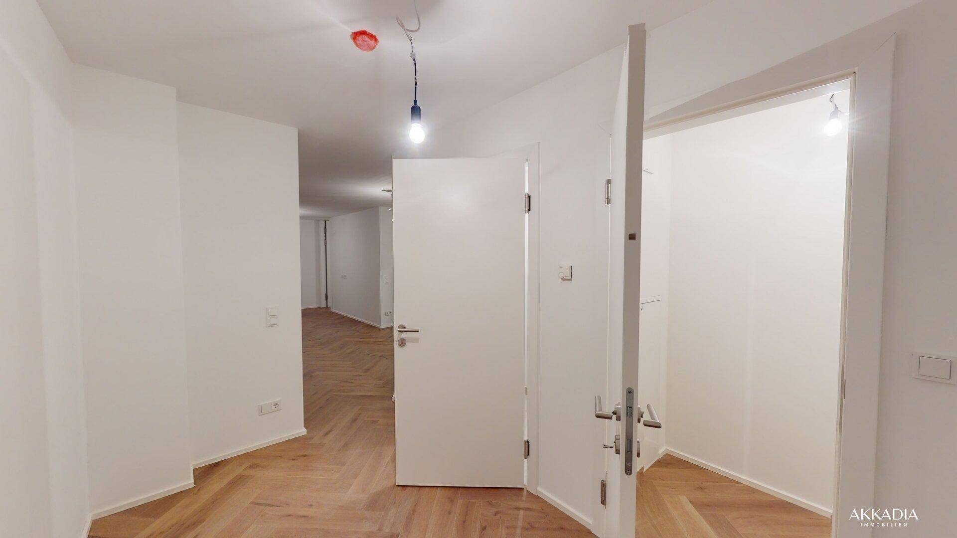 Heller Flur mit Fischgrätparkett und mehreren Türen, der verschiedene Räume verbindet.