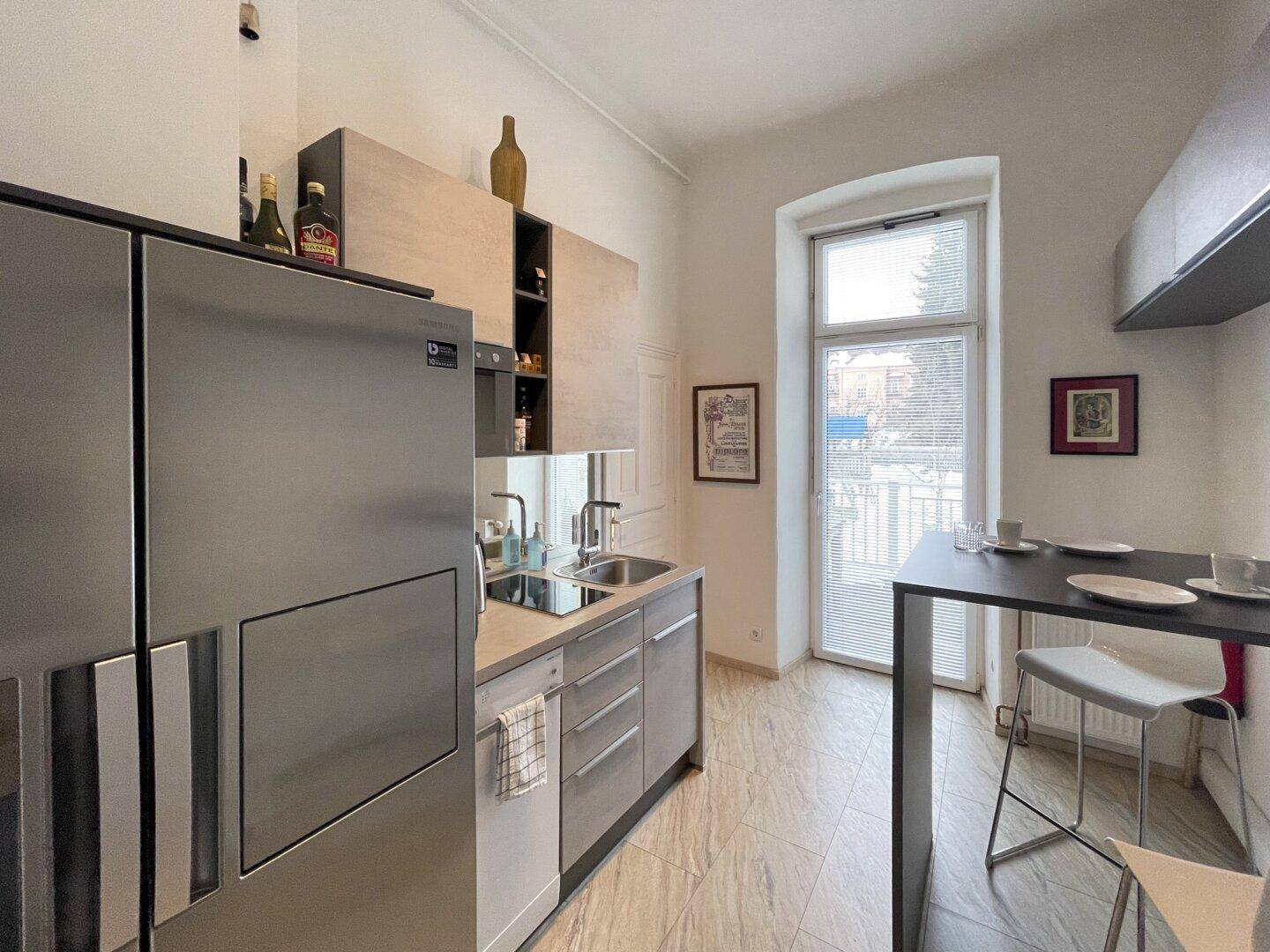 Helle Küche mit großem Kühlschrank, Bartresen und einem Fenster mit Blick nach draußen.