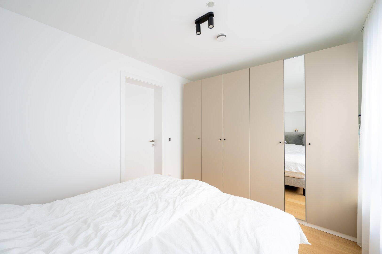 Schlafzimmer mit komfortablem Bett und praktischen Einbauschränken mit Spiegelfront.