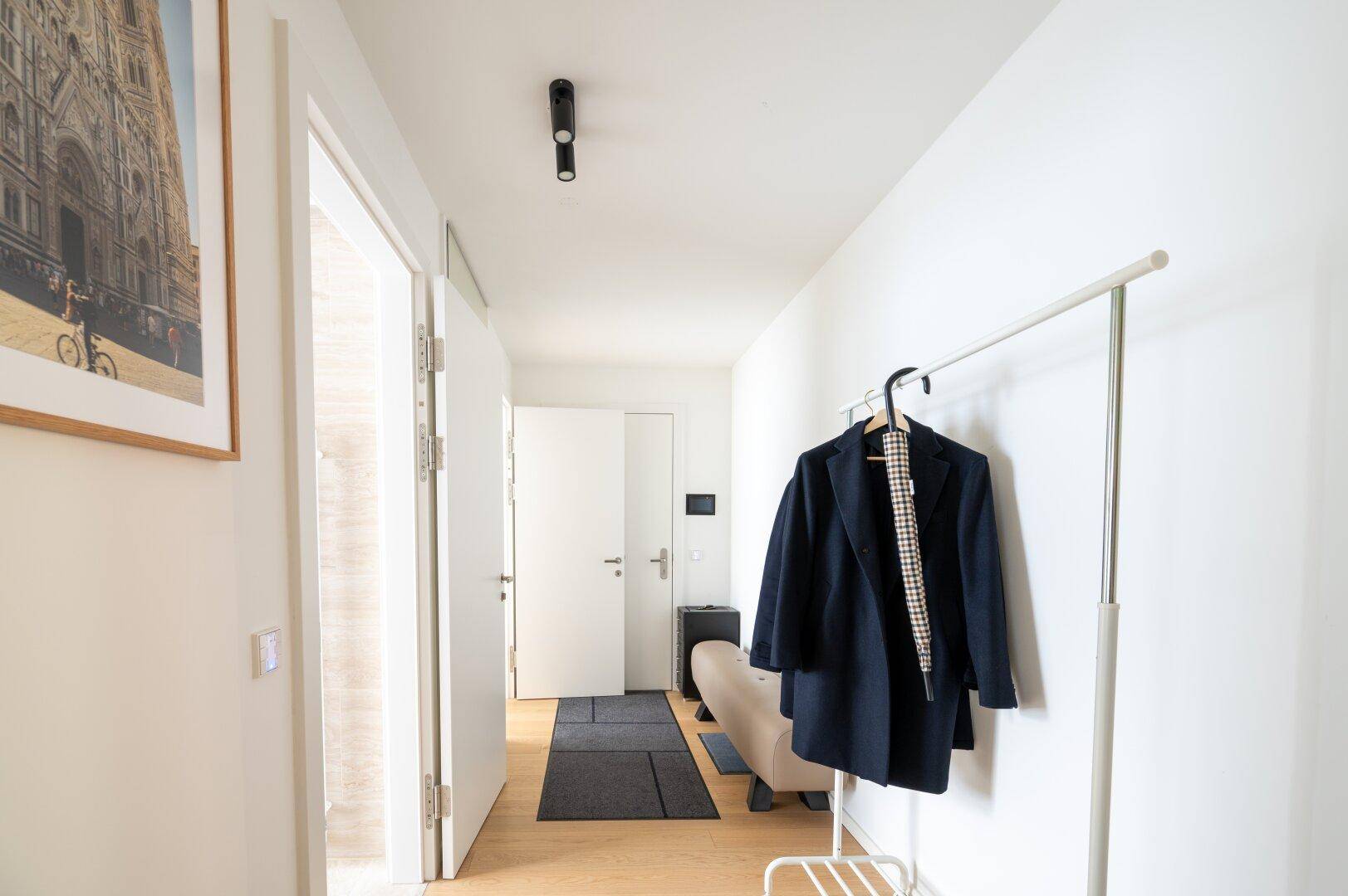 Heller Eingangsbereich mit Garderobe und modernem Design, der zu den Wohnräumen führt.