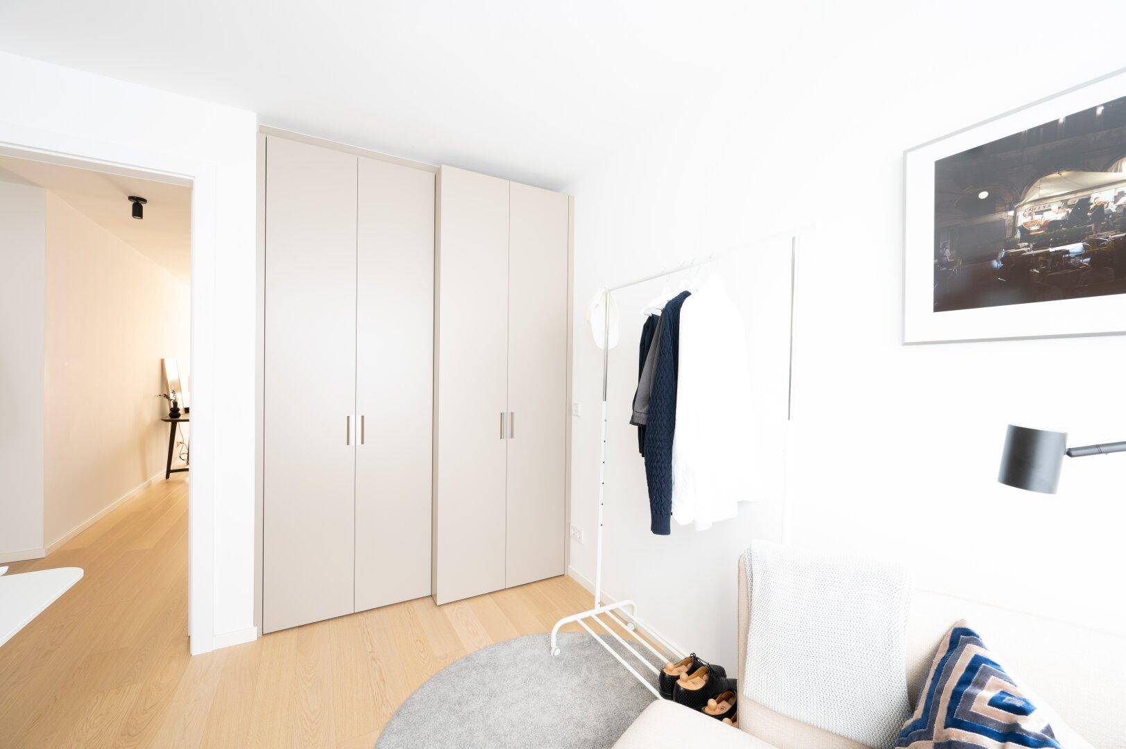 Arbeitszimmer mit praktischen Kleiderschränken und einem Kleiderständer für zusätzlichen Stauraum.