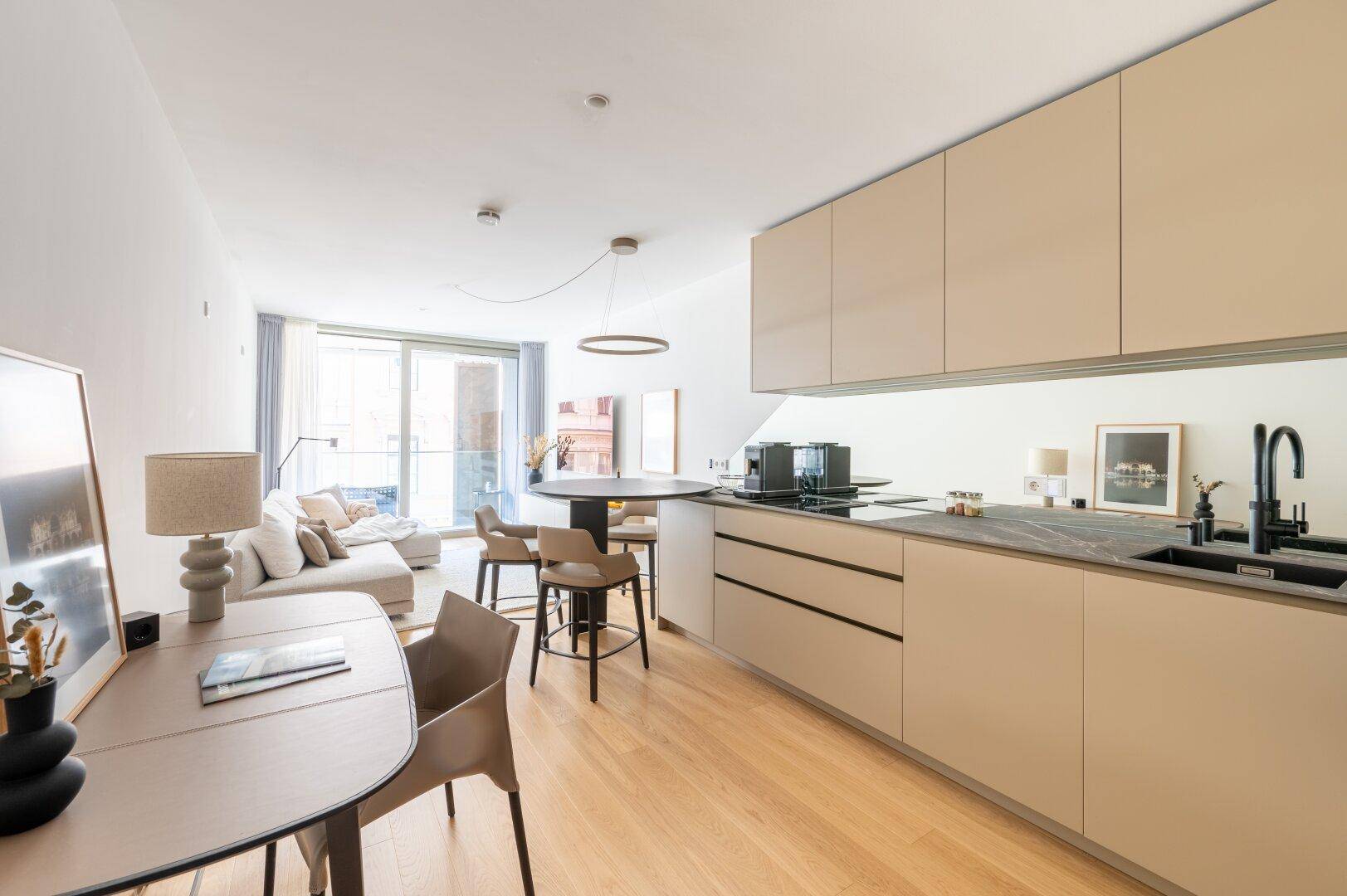 Offener Wohn- und Essbereich mit moderner Einbauküche, Esstisch und Zugang zum Balkon.