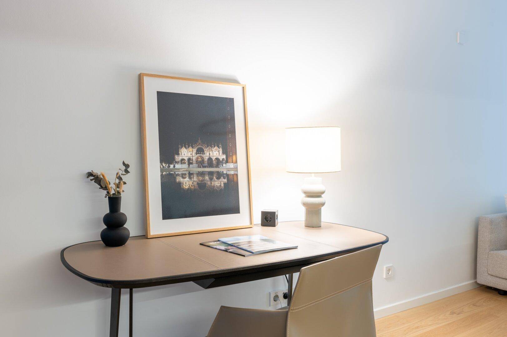 Heller Arbeitsbereich mit modernem Schreibtisch, Stuhl und dekorativer Tischlampe.