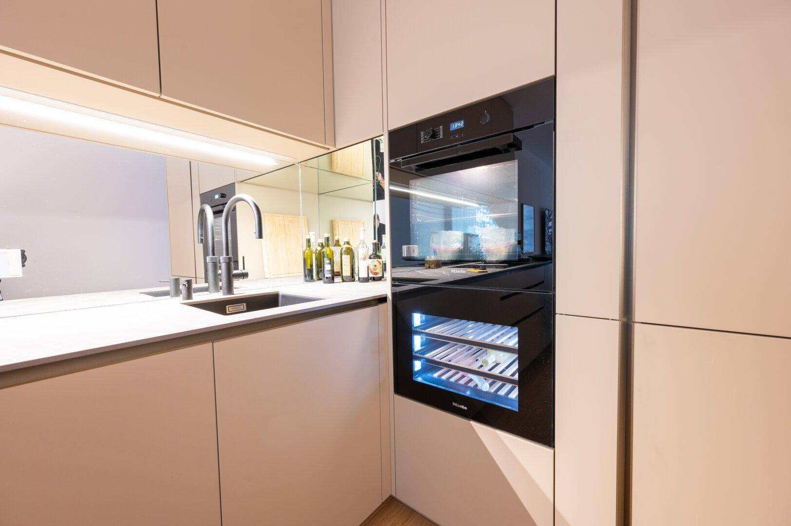 Hochwertige Einbauküche mit Spüle, integriertem Backofen und Weinkühlschrank.
