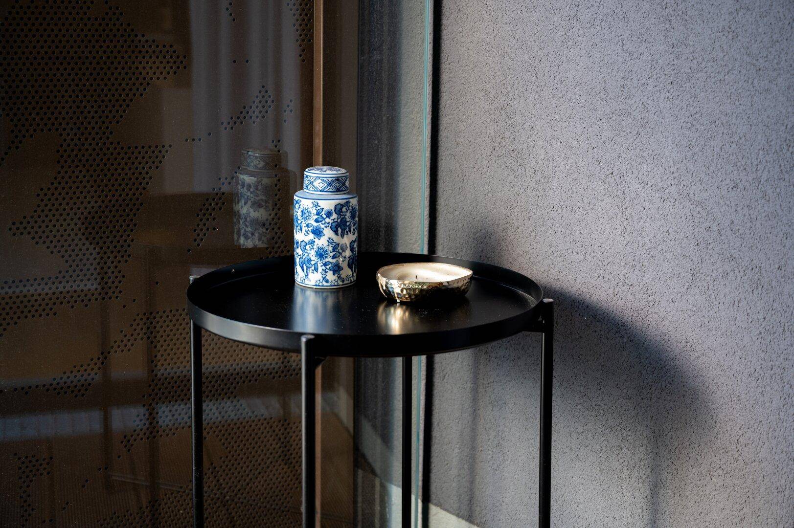 Detailansicht eines kleinen Beistelltisches mit dekorativer Vase und Kerze.