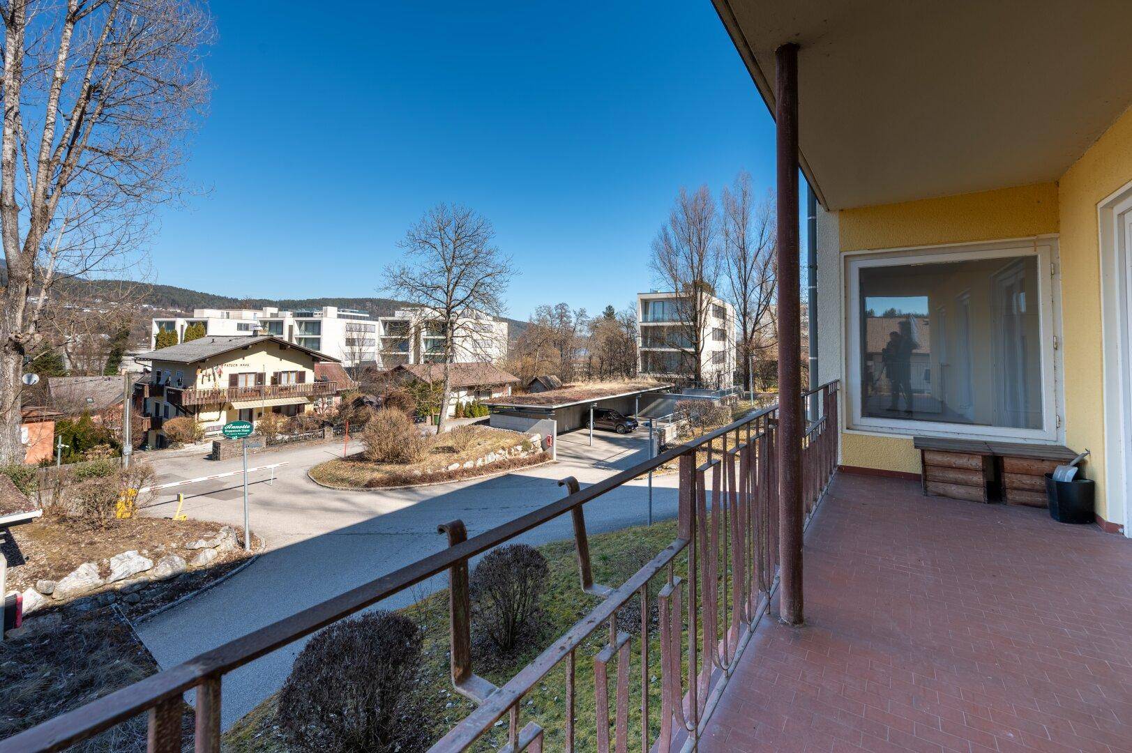 Geräumiger Balkon mit Blick auf eine Straße, umliegende Häuser und die bergige Landschaft.