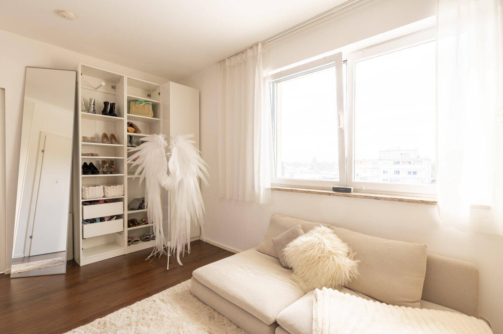 Helles Zimmer mit Kleiderschrank, Sofa und großem Fenster, ideal als Ankleide- oder Gästezimmer.