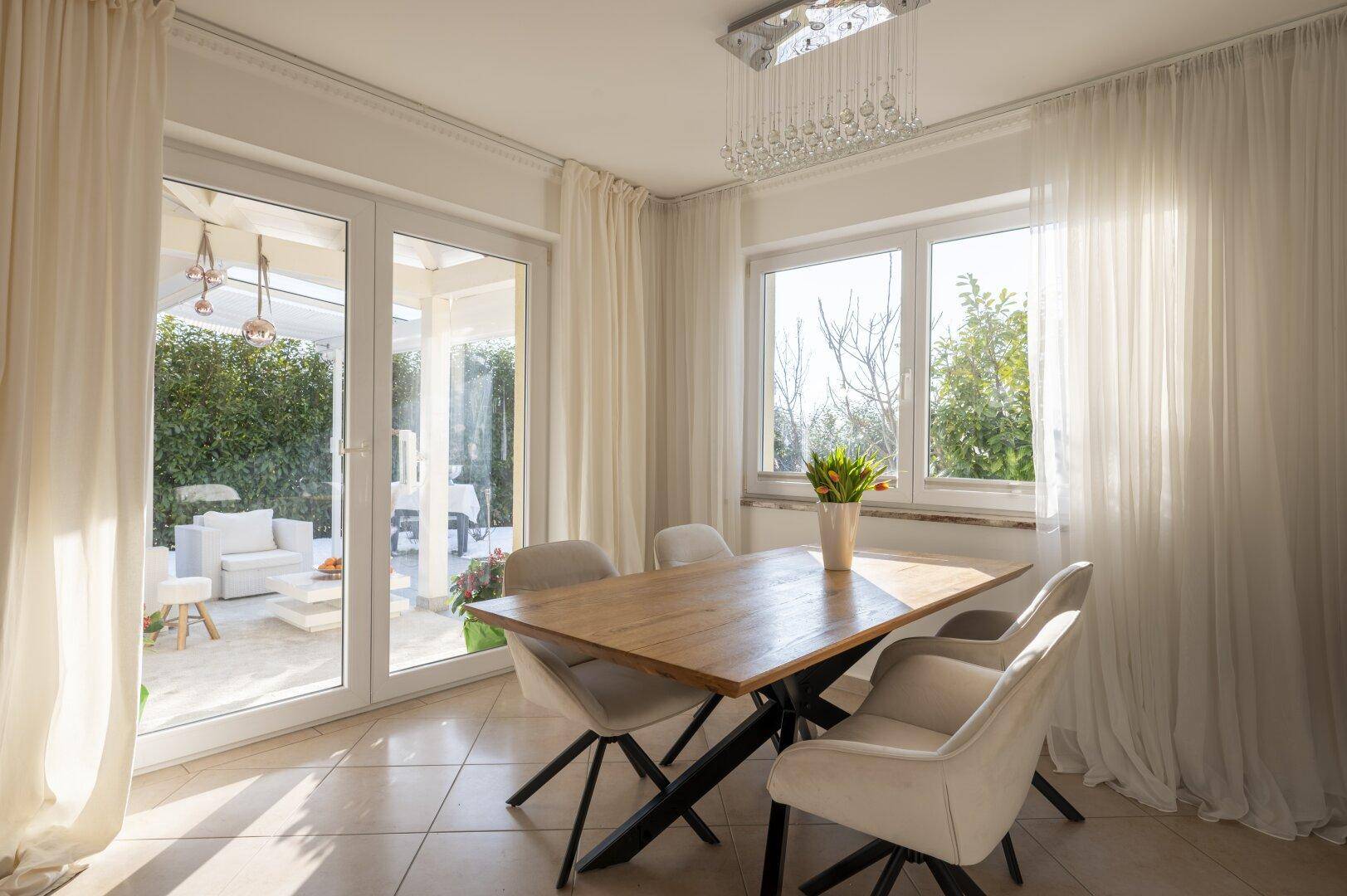 Heller Essbereich mit Holztisch, modernen Stühlen und Zugang zu einer Außenterrasse.